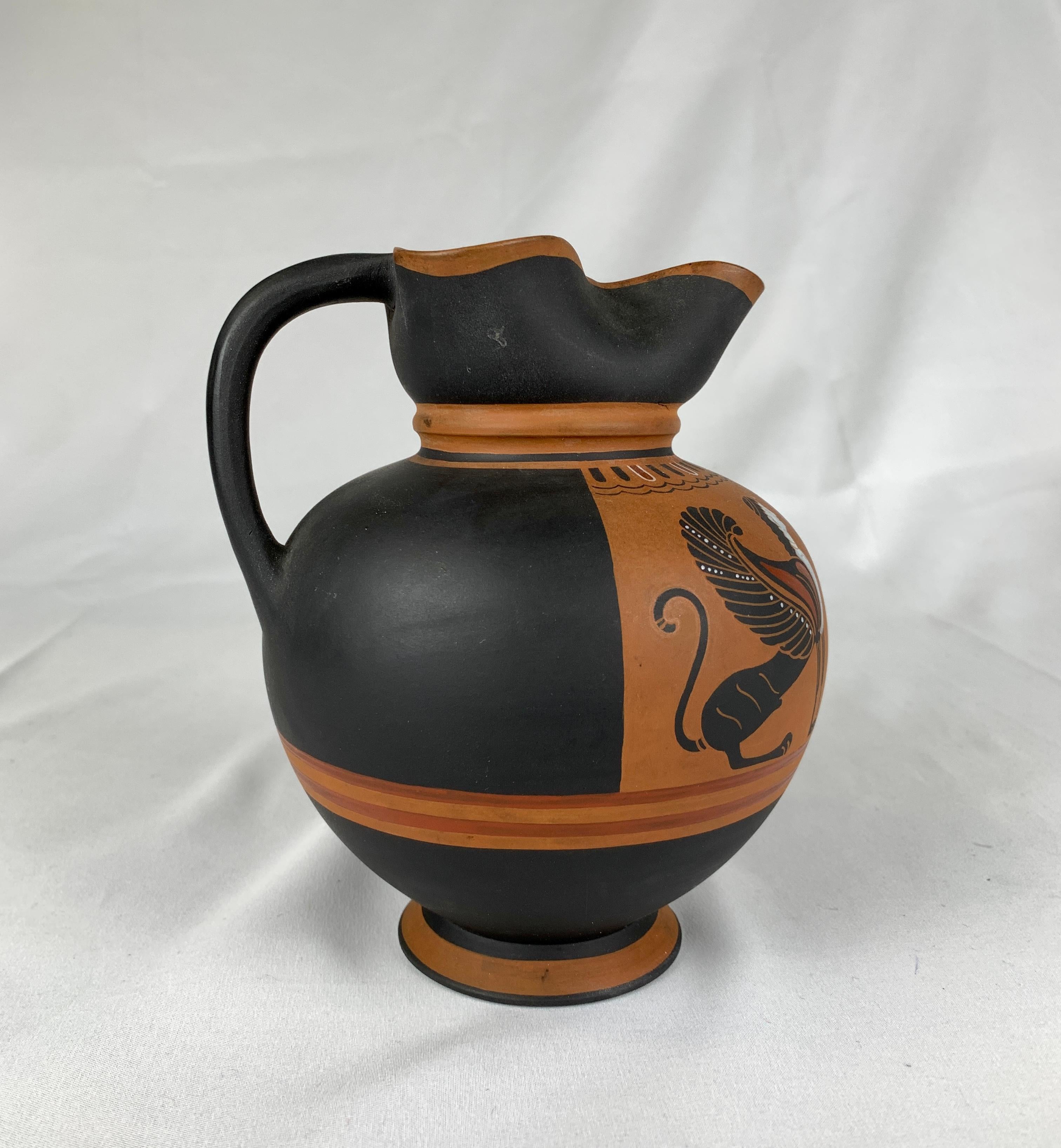 This special edition Wedgwood ale jug is decorated in Egyptian Revival style, showing a sphinx to either side of a firebird in flight. The material is Wedwood's Black Basalt stoneware with Wedgwood's Rosso Antico decoration in the Greek black-figure