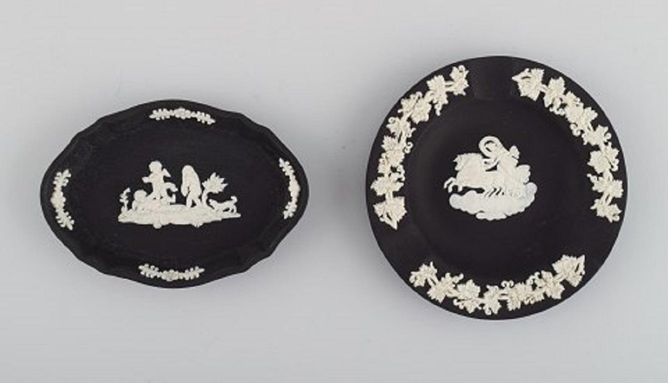 Wedgwood, England. Three bowls/dishes and a flowerpot in black, green and blue stoneware with classicist scenes in white. 
Early 20th century.
The flowerpot measures: 7.5 x 6.8 cm.
Round bowl / dish diameter: 11.2 cm.
Stamped.
In excellent