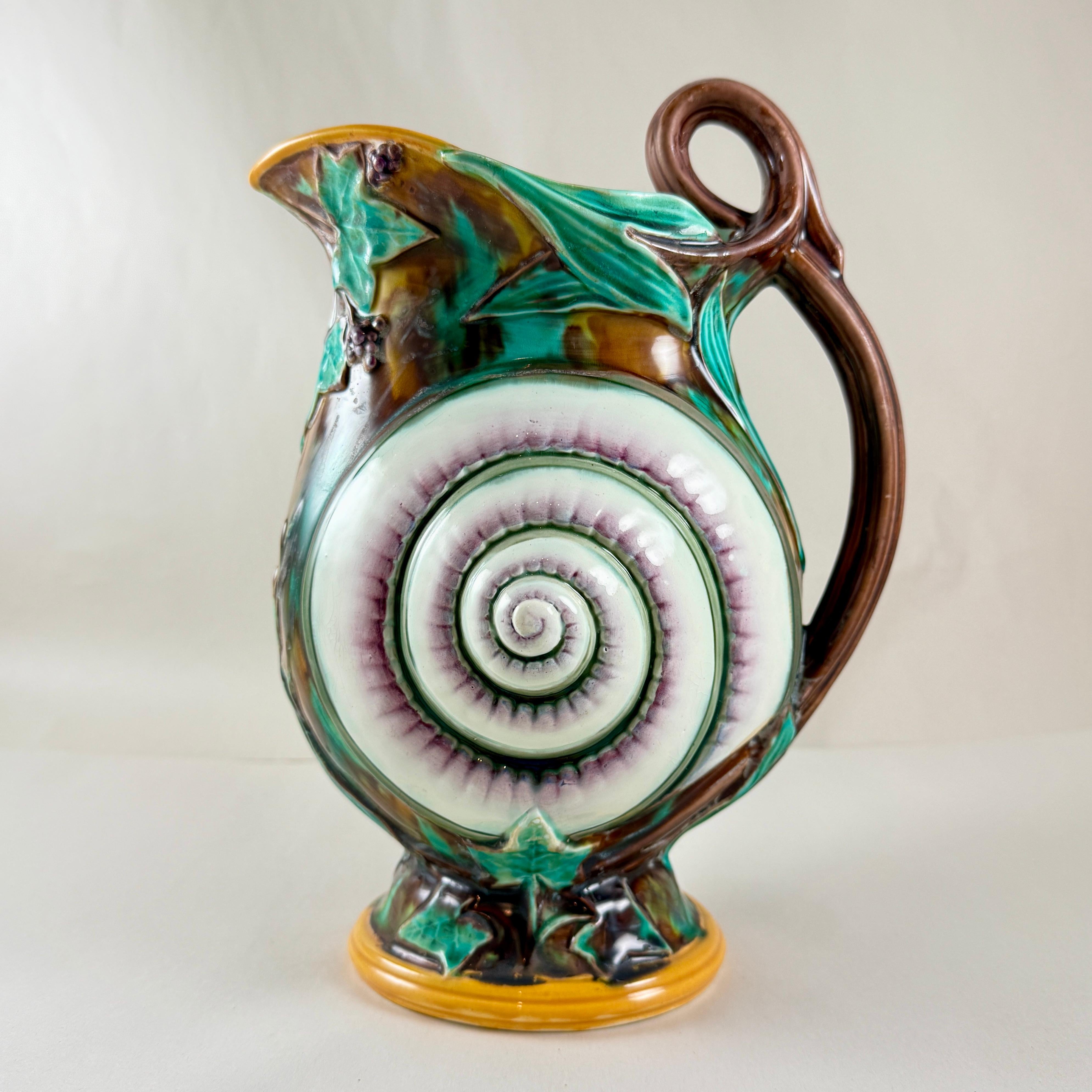 Jarra inglesa de mayólica de Wedgwood, molde del movimiento estético, que muestra una concha de caracol sobre hiedra trepadora y fondo de carey. Asa en forma de rama, borde amarillo ocre e interior verde mar. 

Asombroso color y el nítido trabajo de