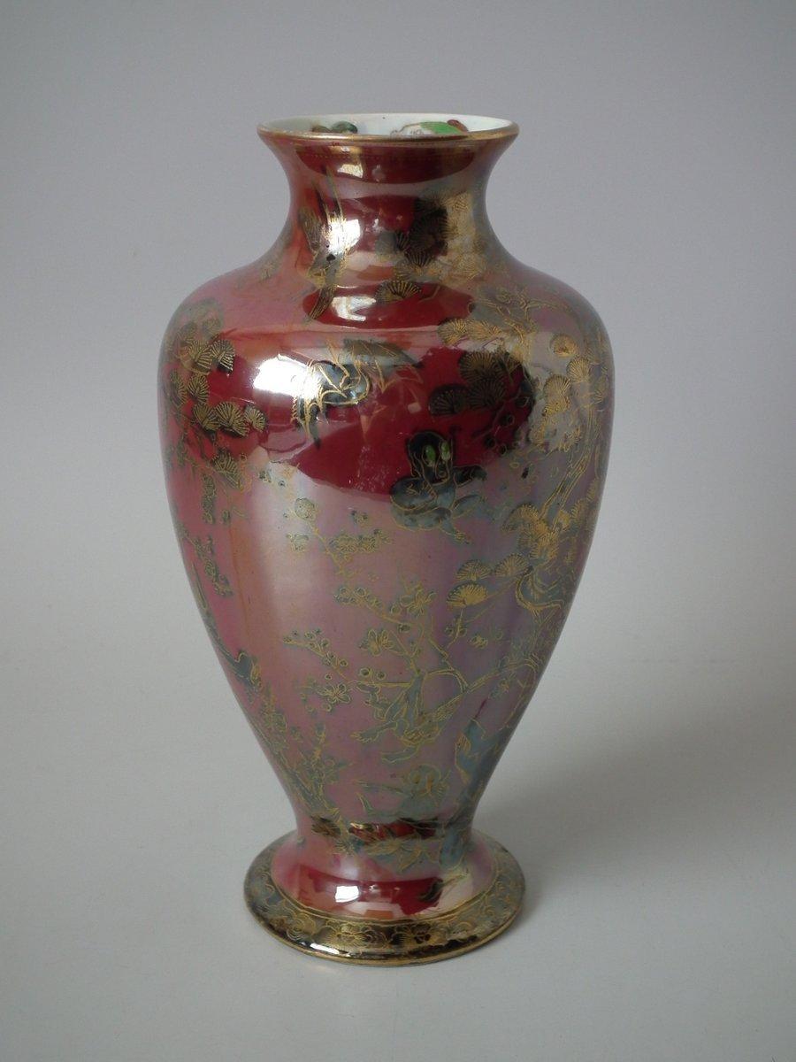Wedgwood fairyland lustre vase. The vase is decorated in the Firbolgs IV pattern, which features comical, accident-prone 'firbolgs'. The inside of the rim features three colorful fish. Ruby ground with black and gold overlay. Wedgwood Portland vase