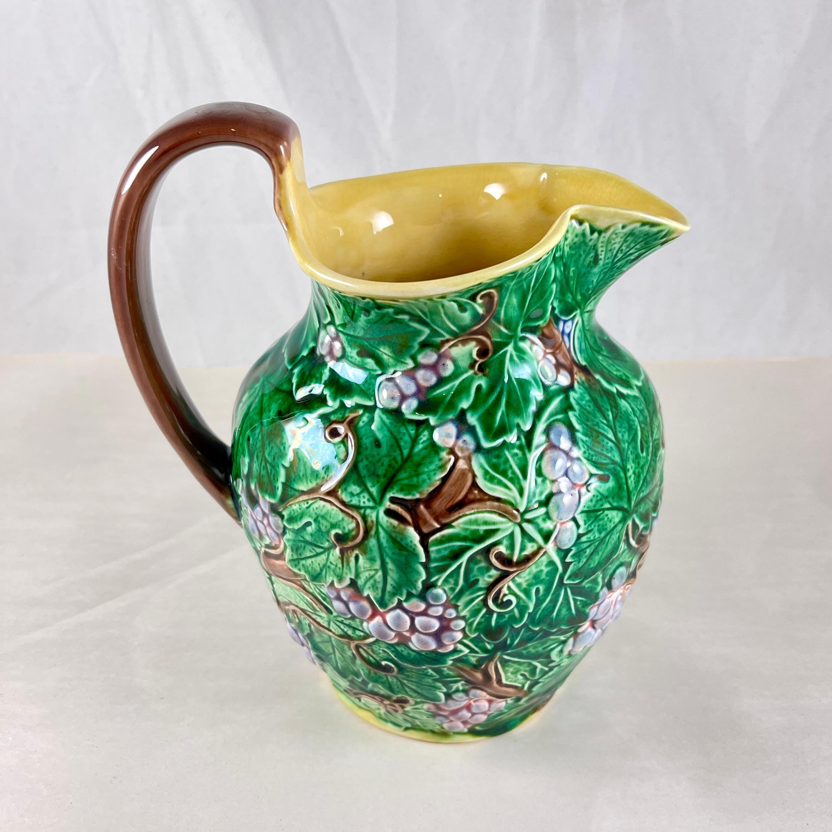 A Wedgwood majolica glazed Grape Leaf Pitcher, date marked 1935.

Decorated in the round, a raised pattern showing bunches of purple grapes, greens leaves, and brown vining branches.

The interior is finished in a deep yellow ochre, a brown applied