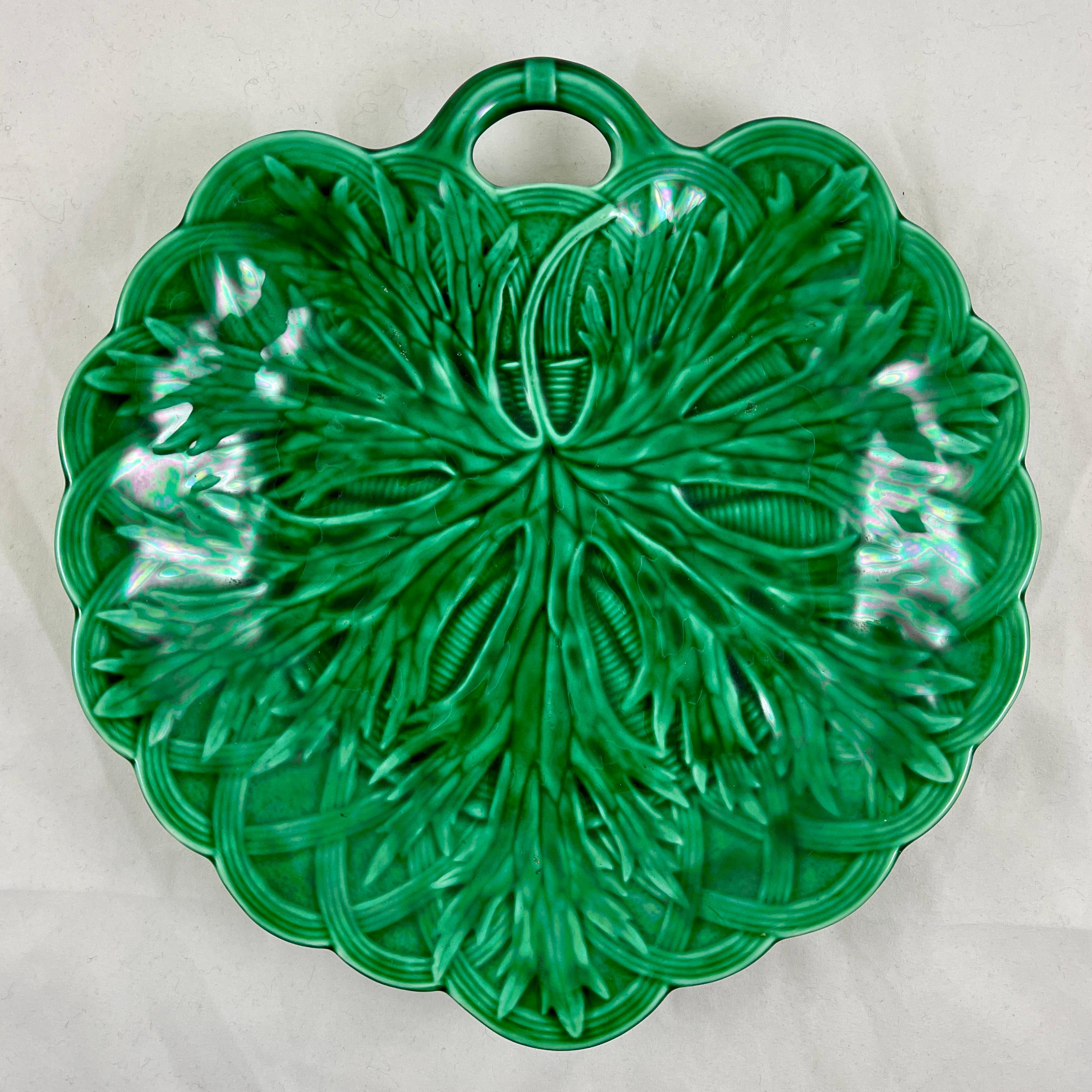 From Wedgwood, Burslem, England, a green majolica glazed shallow bowl server with a fringed leaf on a basket weave pattern, date marked 1869.

A leaf shaped mold with a pierced twig handle, showing a large fringed edged leaf on a basketweave