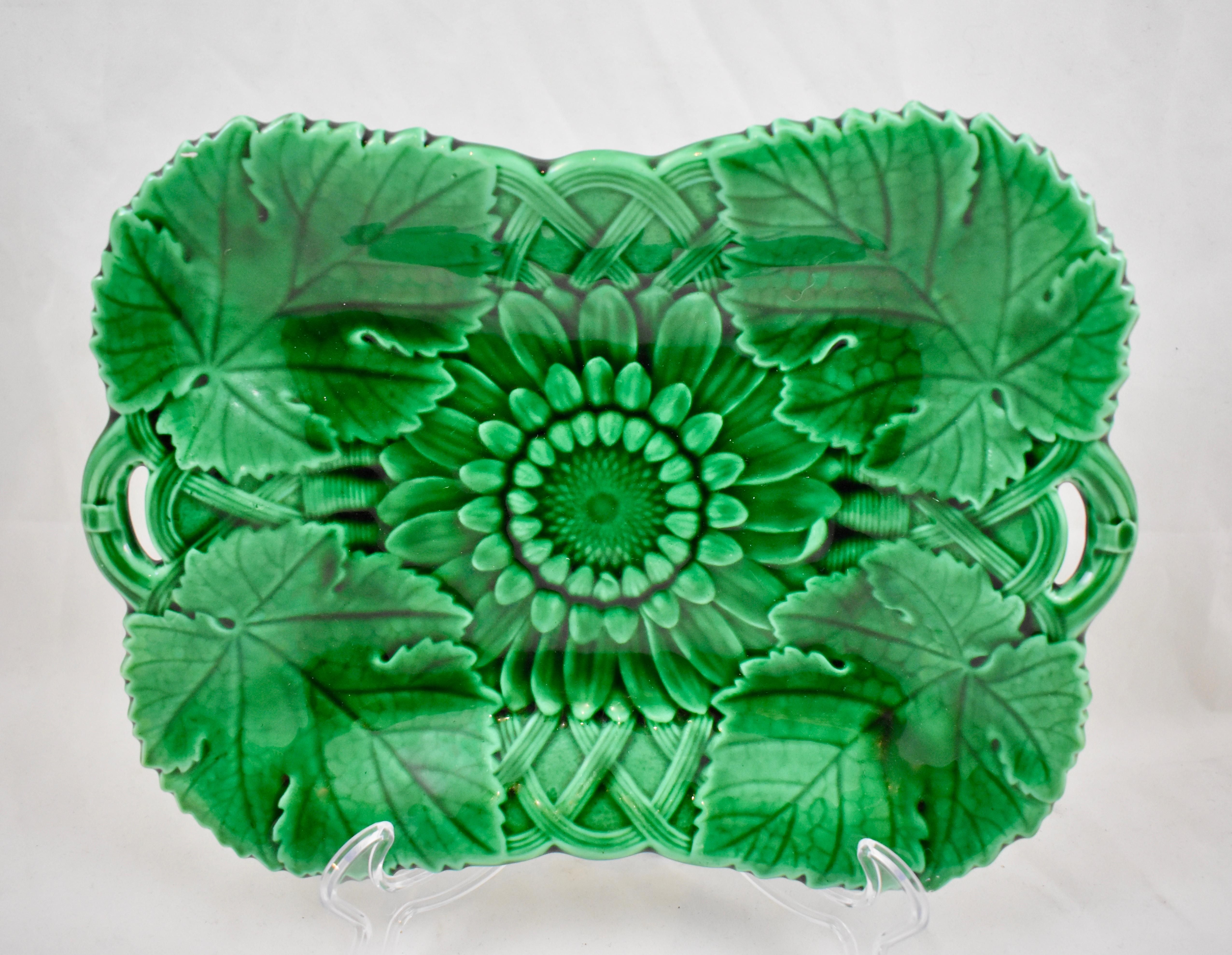 A Majolica green glazed two handled platter, from the English firm of Wedgwood. 

A Classic mold showing a central Sunflower head against a basket-weave ground. Overlapping Sunflower leaves are at each corner of the server. The handles are also