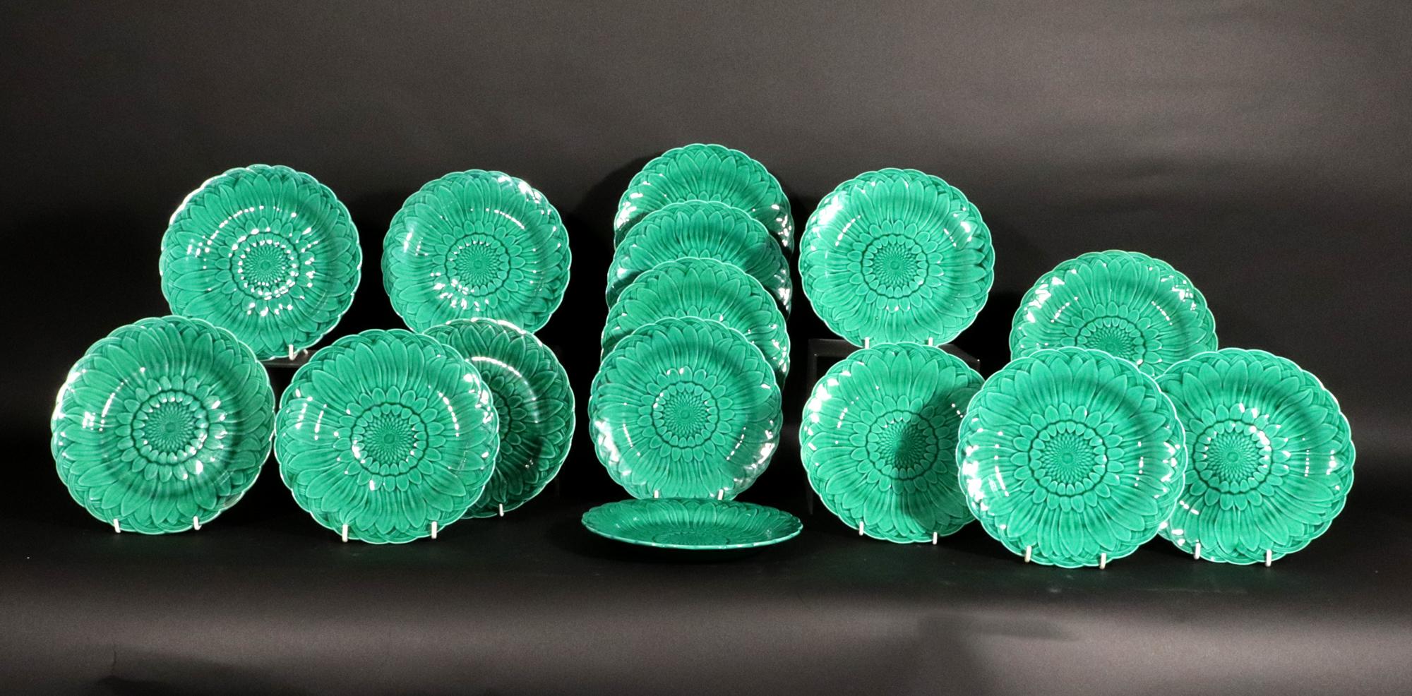 Platos de girasol de mayólica verde de Wedgwood Pottery,
Aesthetic Movement,
Quince láminas,
Alrededor de 1860

El juego de mayólica Wedgwood de quince platos tiene un diseño de girasol moldeado dentro de un borde de tejido de cesta con gran