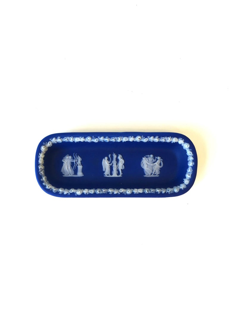 An antique Wedgwood Jasperware blue and white oblong jewelry dish in the Neoclassical Style, circa late-19th century, England. Piece has a slightly folded lip with raised detail around edge and three raised figural relief scenes across. Marked on