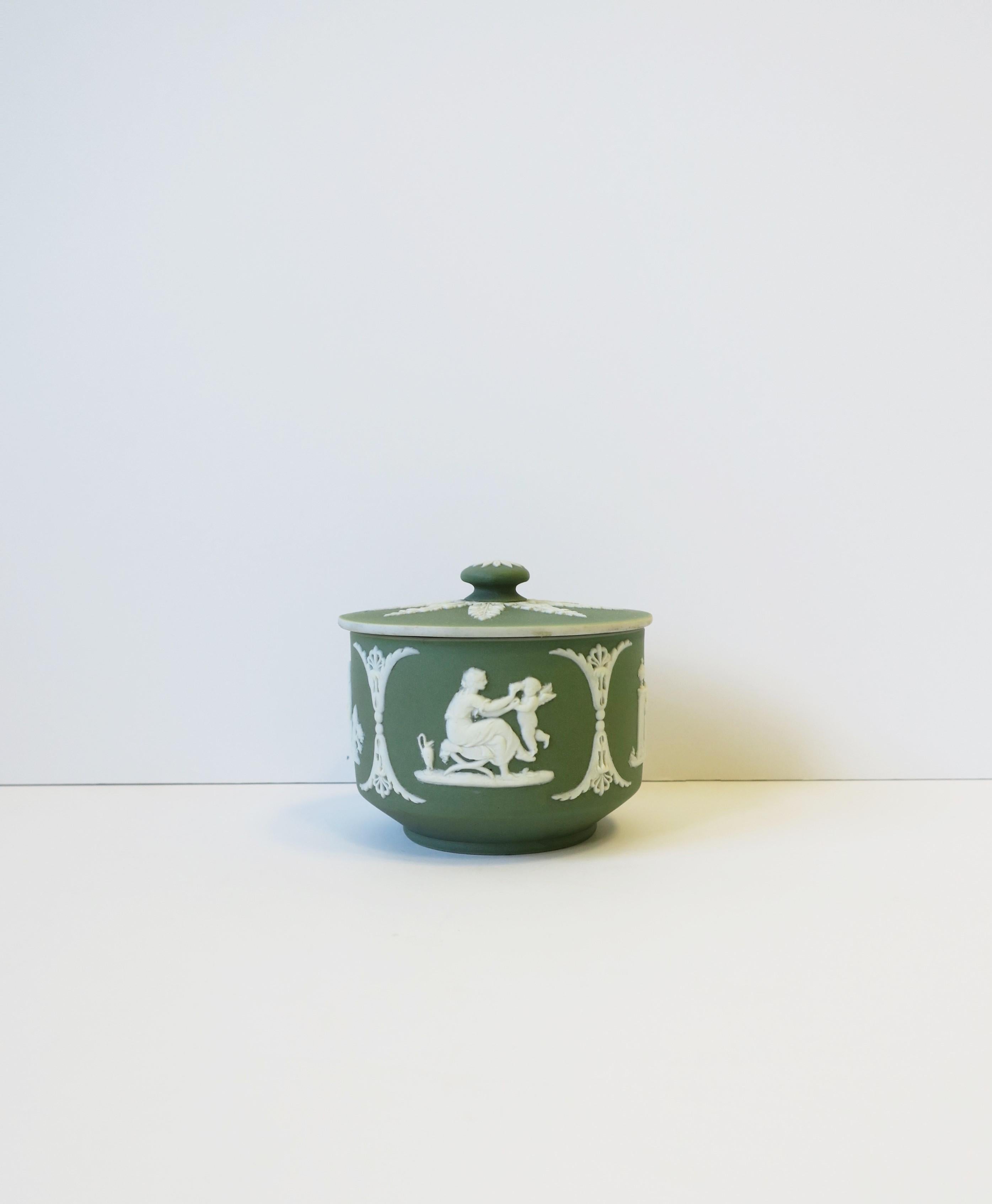 A beautiful English green and white Jasperware matte stoneware round box by Wedgwood in the Neoclassical style, circa late-19th century, England. Lid features with knot top has a detailed raised relief leaf design in white. Other beautiful