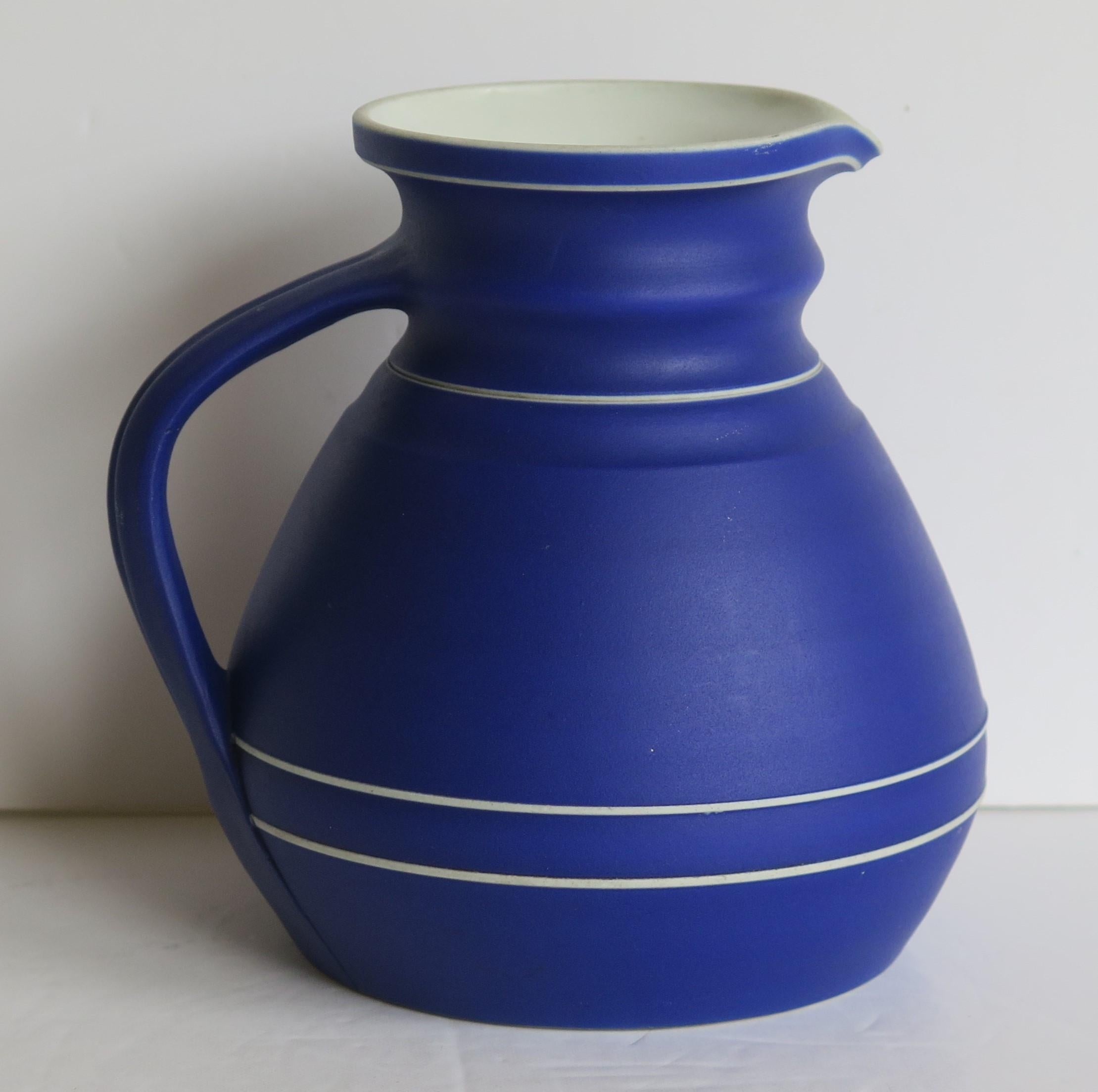 This is a fine early Jasperware stoneware water jug or pitcher in the rarer dark blue ground, made by WEDGWOOD, England in the mid 19th Century, 1850 

The jug has a lovely shape with a pouring spout and loop handle.

This piece is fully marked