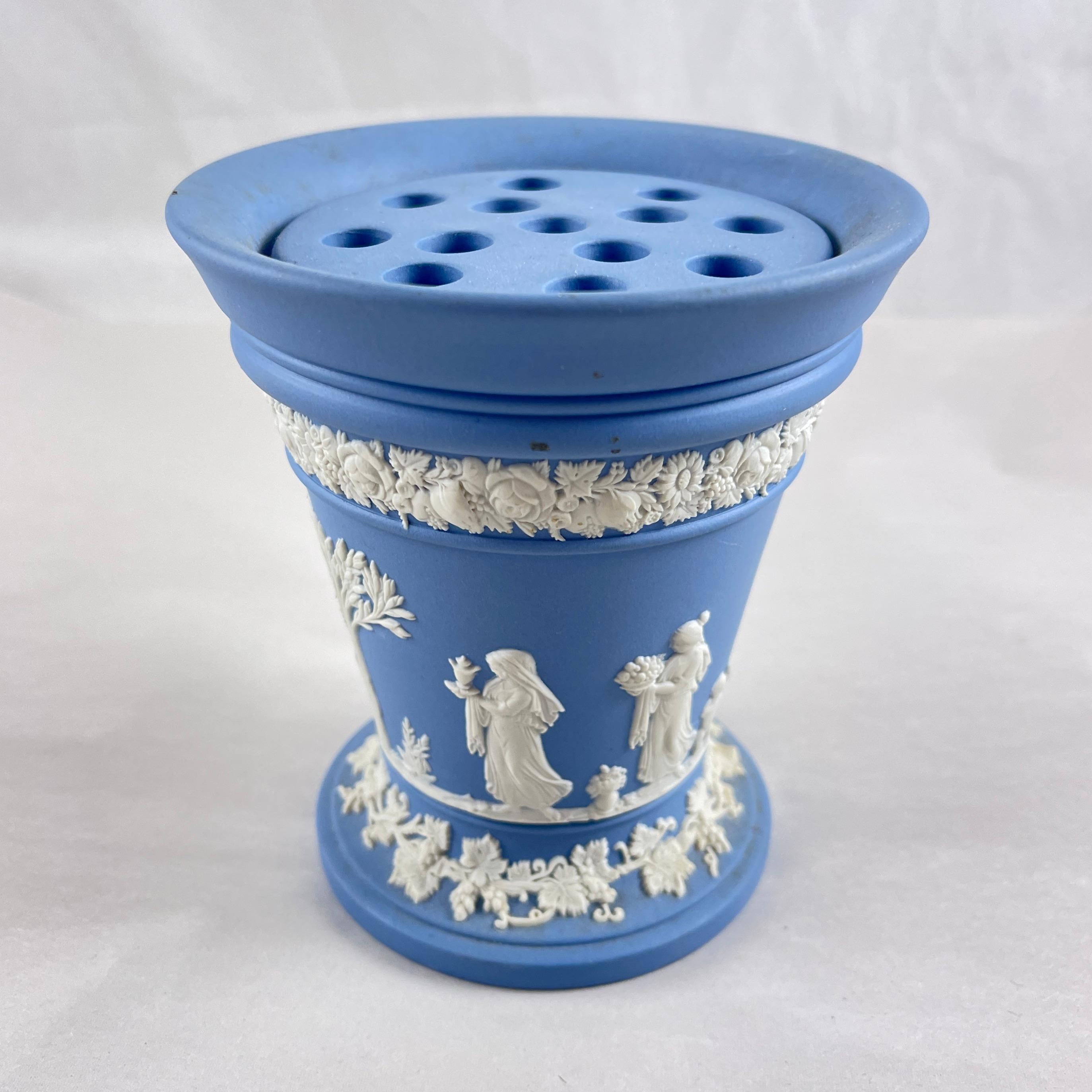 Vaso neoclassico in gres blu e bianco di Wedgwood Jasperware con inserto di fiori a rana, datato 1968.

Il vaso è decorato a rametti con figure classiche e con un bordo floreale in corrispondenza della parte superiore e del fondo, il tutto in