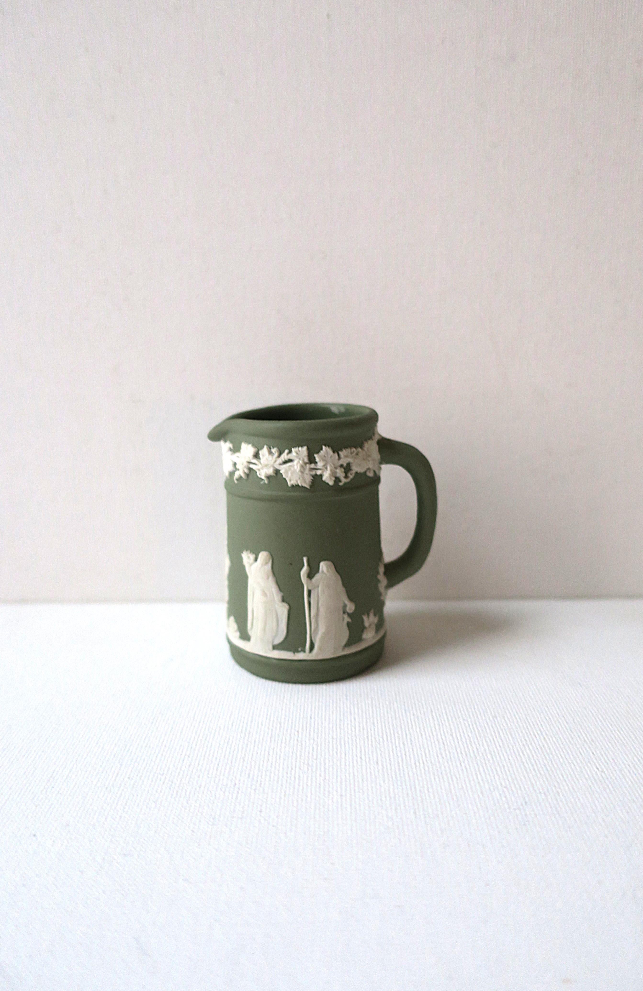 An authentic English sage green and white Jasperware matte stoneware pitcher by Wedgwood in the Neoclassical style, 1955, mid-20thth century, England. Pitcher has a white raised relief of grapes, leaves and vines, around top, base and center area