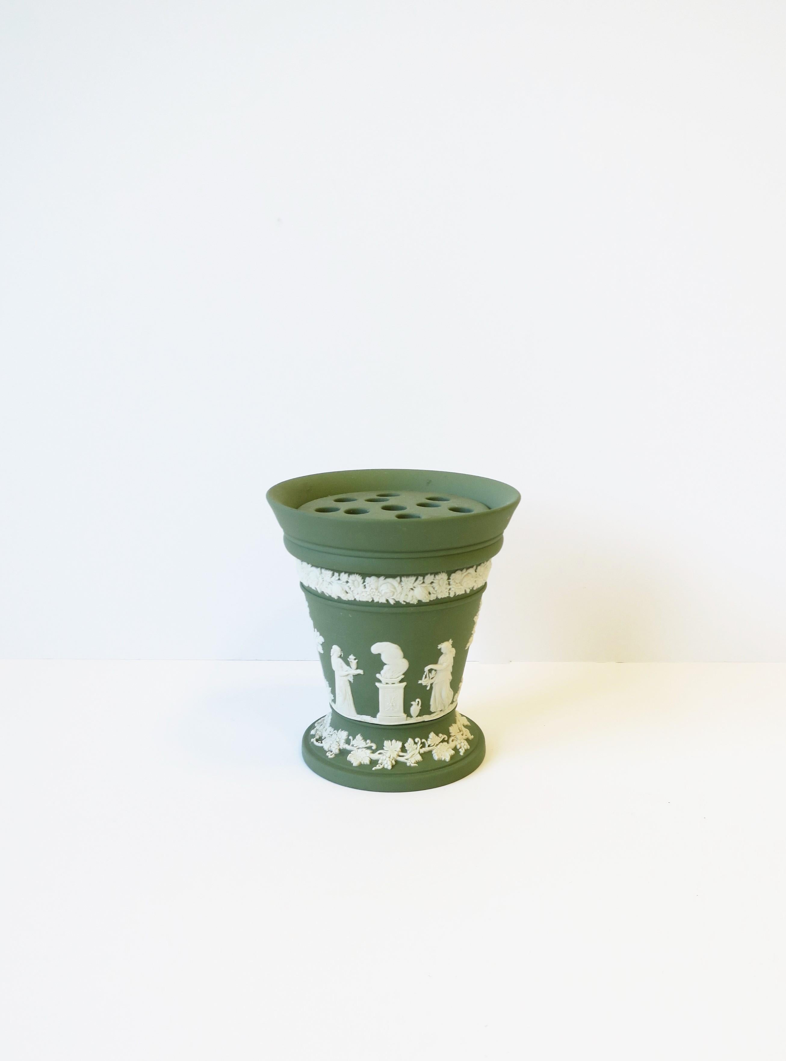 A beautiful English Wedgwood sage green and white matte Jasperware stoneware vase in the Neoclassical design style, 1974, 20th century, England. Piece is a matte stoneware in a light green with a white neoclassical raised relief around/center, and a