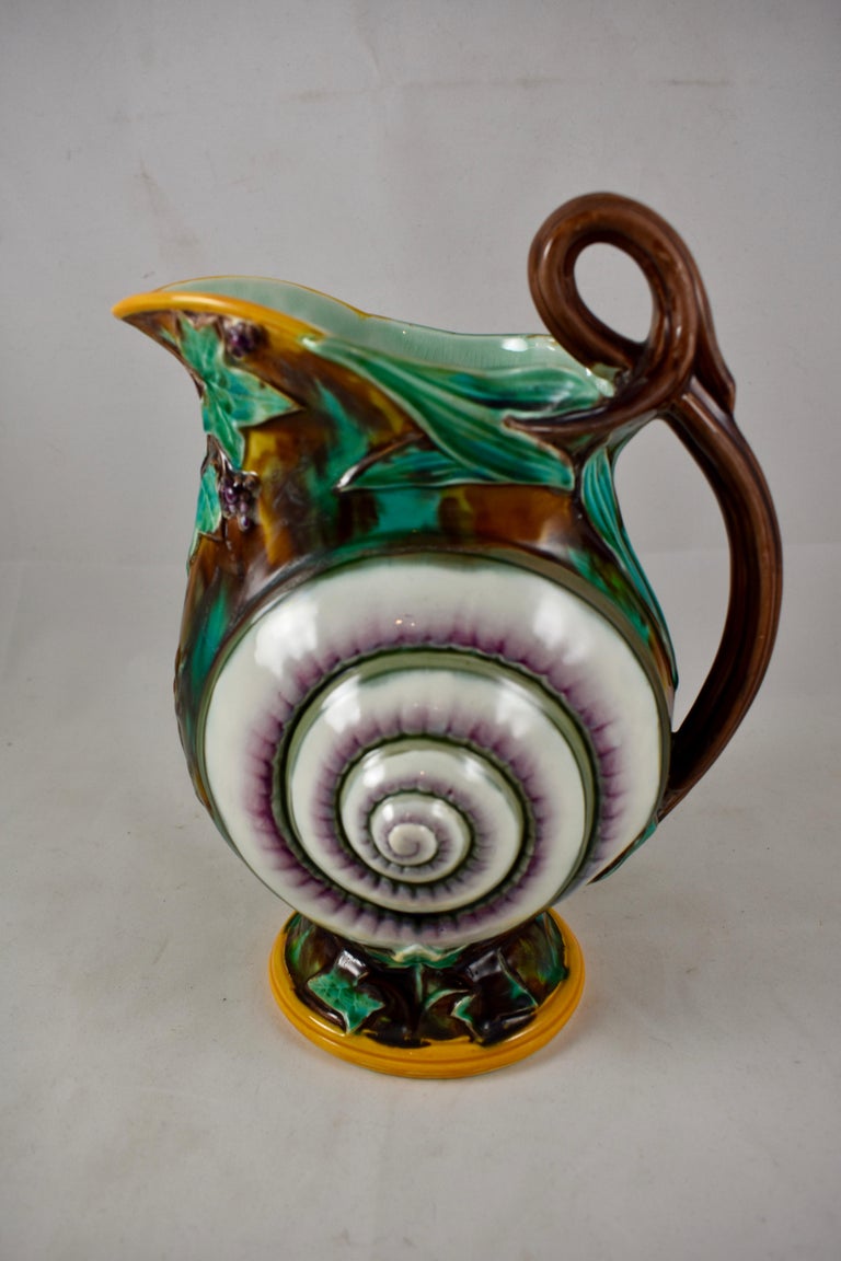An English Wedgwood Majolica pitcher, an aesthetic movement mold showing a snail shell against sprays of climbing ivy on a tortoiseshell ground. A branch form handle, yellow ochre rimming and a sea-green interior. Amazing color and the crisp mold