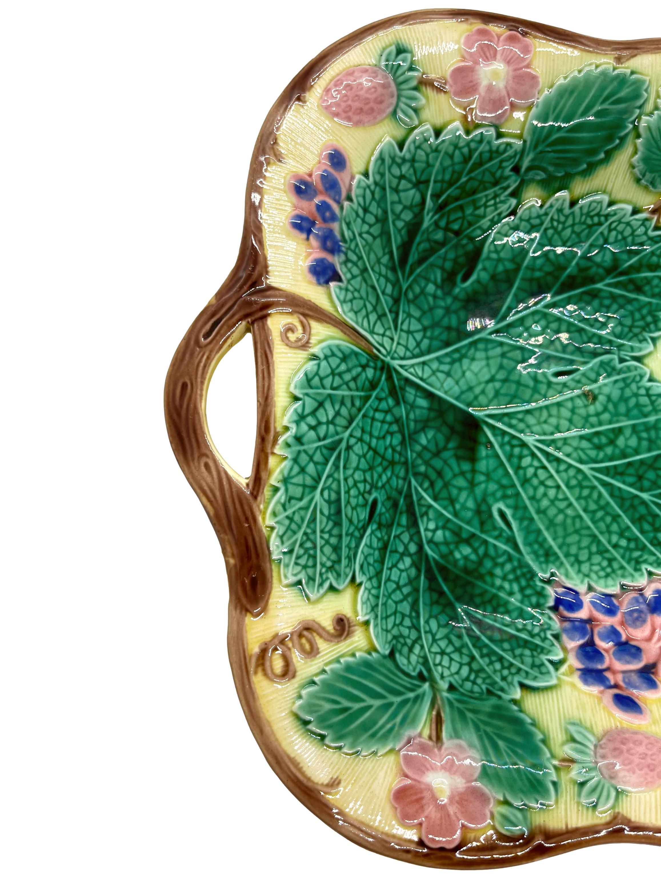 Wedgwood Majolica bread tray, the relief molded dish with purple glazed grapes, pink strawberries and blossoms green grape leaves, bordered in grapevines, the vines forming the handles, the reverse with impressed marks, 'WEDGWOOD', and 'MADE IN