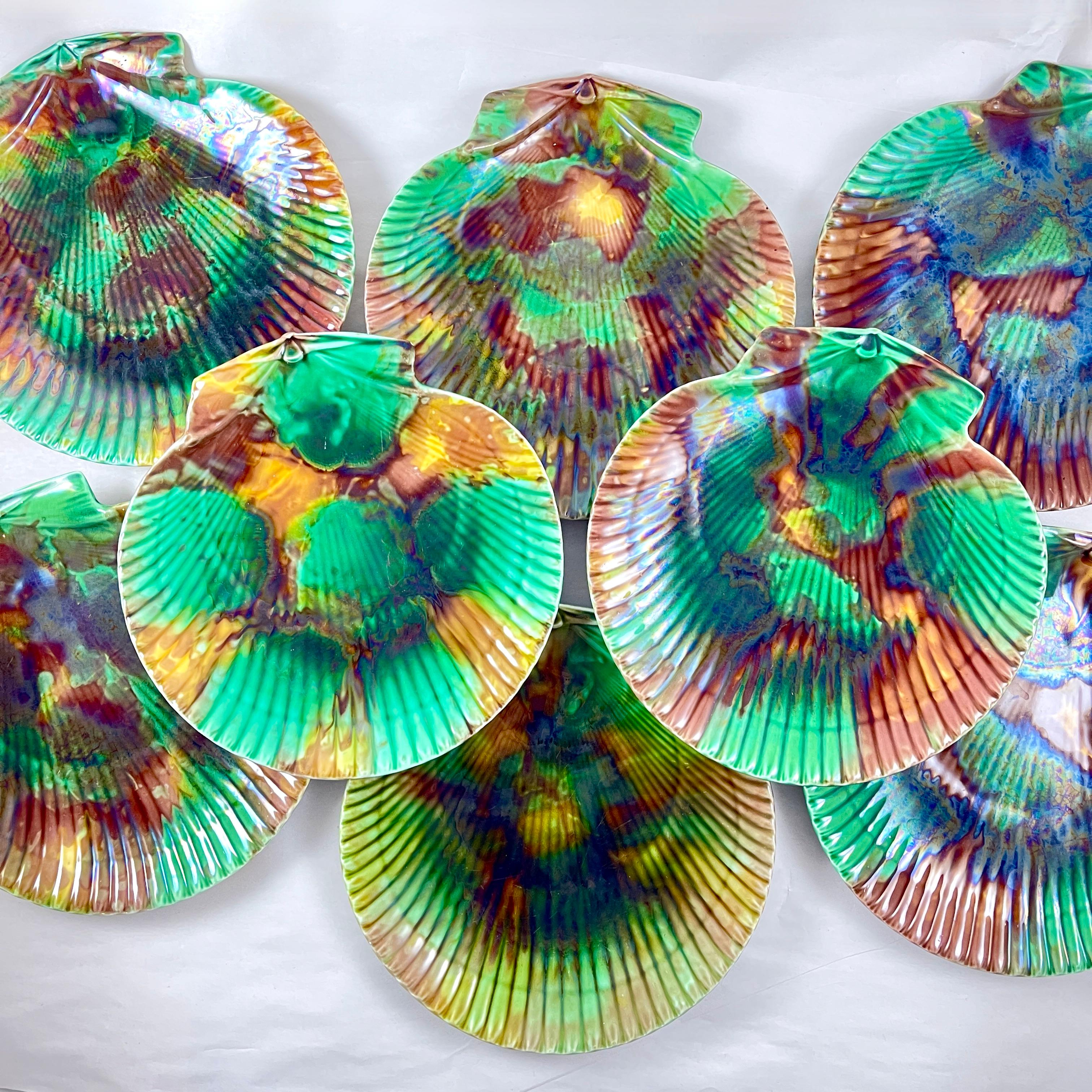 From Wedgwood, an assembled set of eight English majolica scallop shell shaped, mottled tortoiseshell glazed seafood salad plates.

Each plate shows a variation of the tortoiseshell glazing of green, ochre, and brown with an iridescent