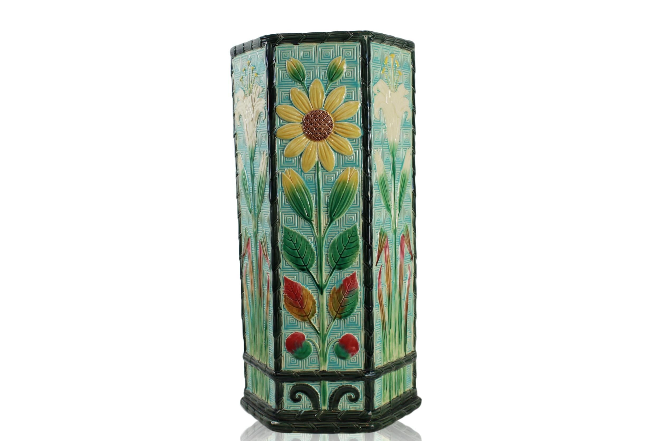 Wedgwood Majolica Aesthetic Movement umbrella stand, 21.75-ins High, with a turquoise fret pattern ground, of hexagonal form, the sides molded with an alternating stylized sunflower and lily, with black glazed reed and ribbon borders, the interior