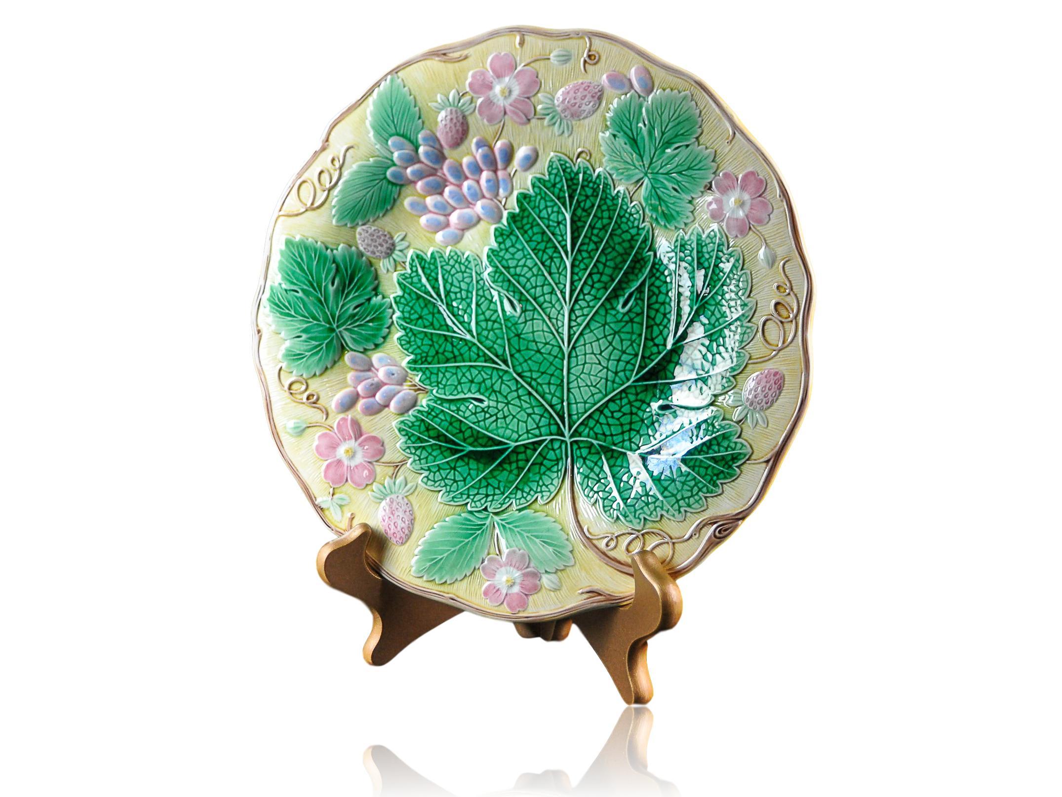 Wedgwood Majolica 'Vine & Strawberry' plate, English, dated 1929, 9-in diameter, with a large central green grape leaf, purple grapes, reddish pink strawberries and blossoms on a yellow ground. Impressed marks to reverse: 'Wedgwood' 'MADE IN