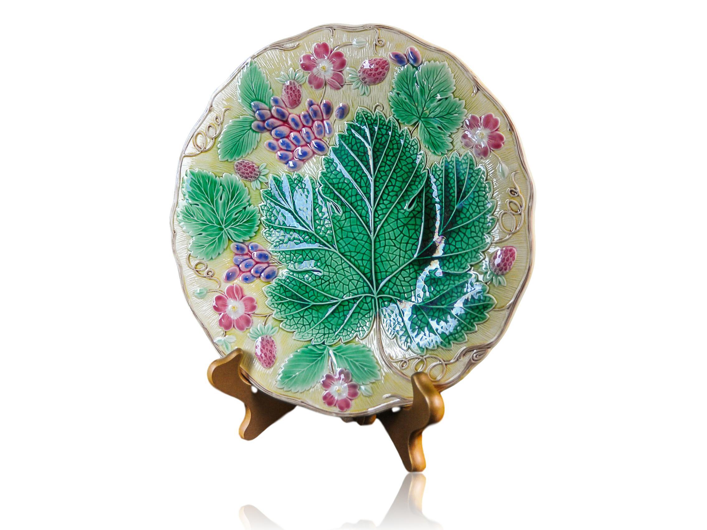 Wedgwood Majolica 'Vine & Strawberry' plate, English, dated 1929, 9-in diameter, with a large central green grape leaf, purple grapes, reddish pink strawberries and blossoms on a yellow ground. Impressed marks to reverse: 'WEDGWOOD' 'MADE IN
