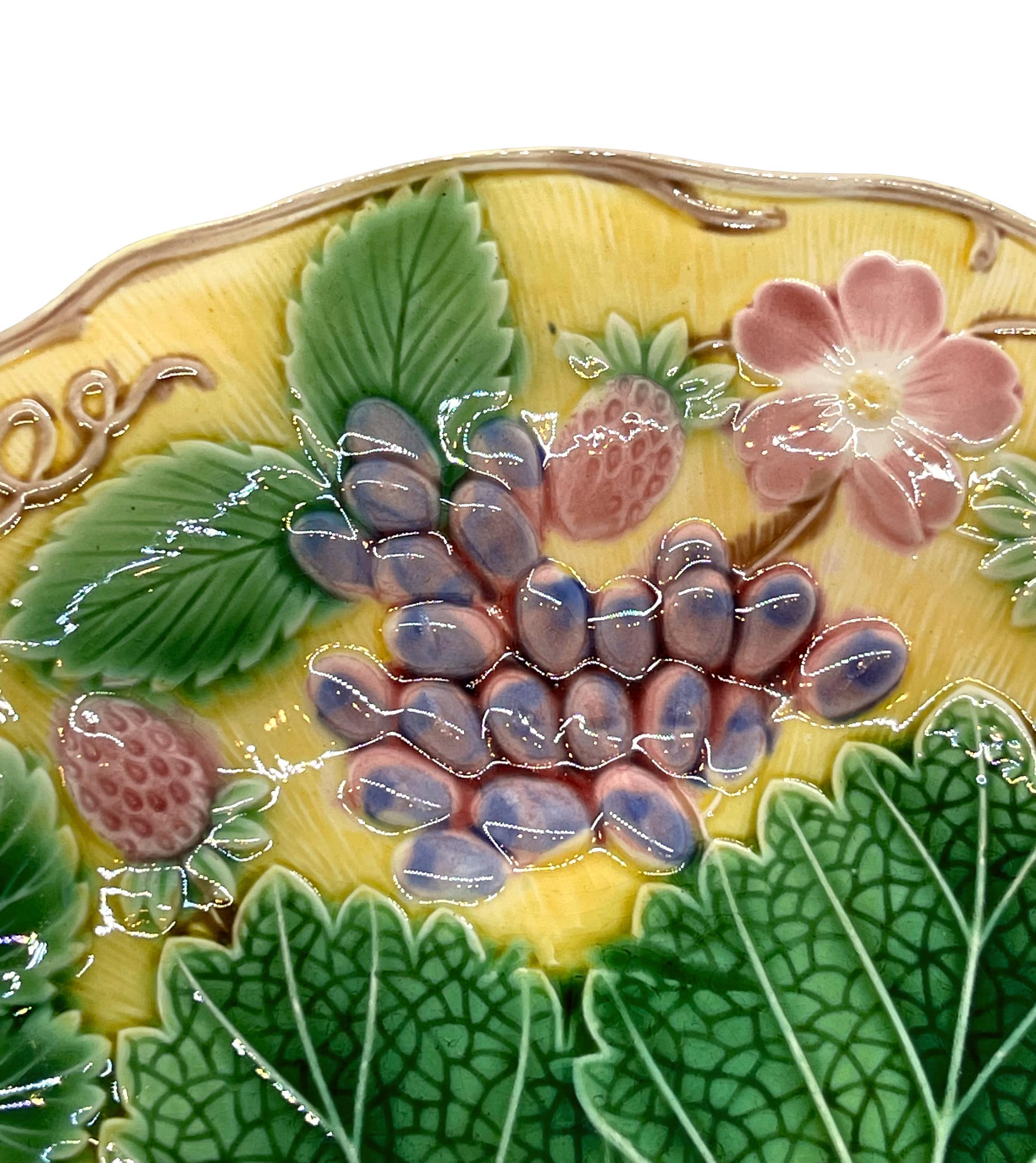 Wedgwood Majolica 'Vine & Strawberry' plate, English, dated 1930, with a large central green grape leaf, purple grapes, reddish pink strawberries and blossoms on a yellow ground. Impressed marks to reverse: 'Wedgwood' 'MADE IN ENGLAND' and the