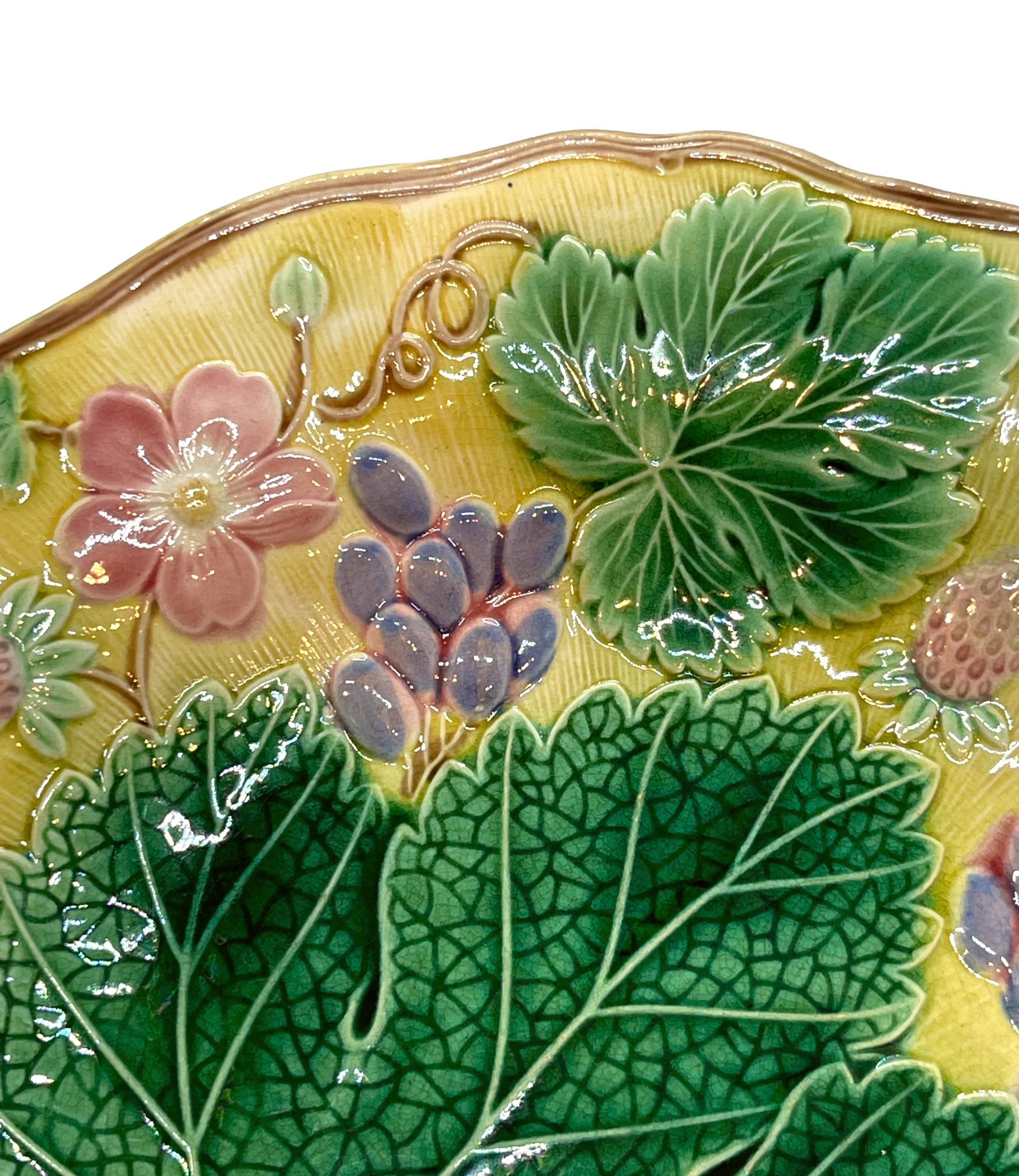 Wedgwood Majolica 'Vine & Strawberry' plate, English, dated 1930, with a large central green grape leaf, purple grapes, reddish pink strawberries and blossoms on a yellow ground. Impressed marks to reverse: 'Wedgwood' 'MADE IN ENGLAND' and the