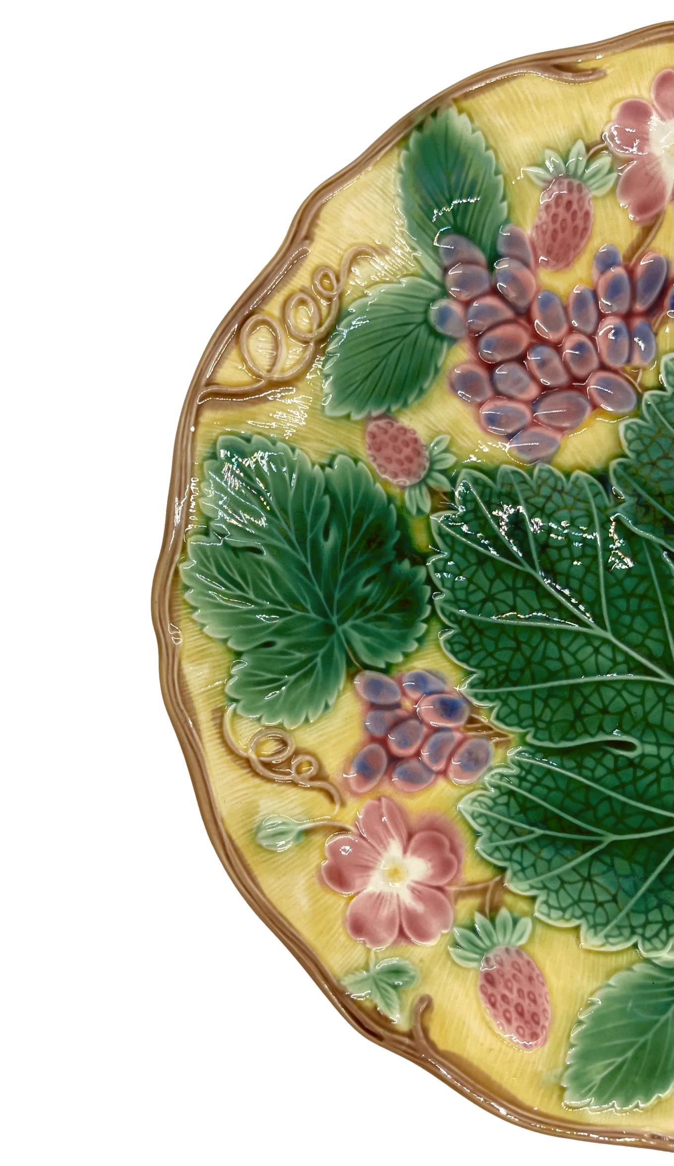 Wedgwood Majolica 'Vine & Strawberry' plate, English, dated 1933, 9-in diameter, with a large central green grape leaf, purple grapes, reddish pink strawberries and blossoms on a yellow ground. Impressed marks to reverse: 'Wedgwood' 'MADE IN