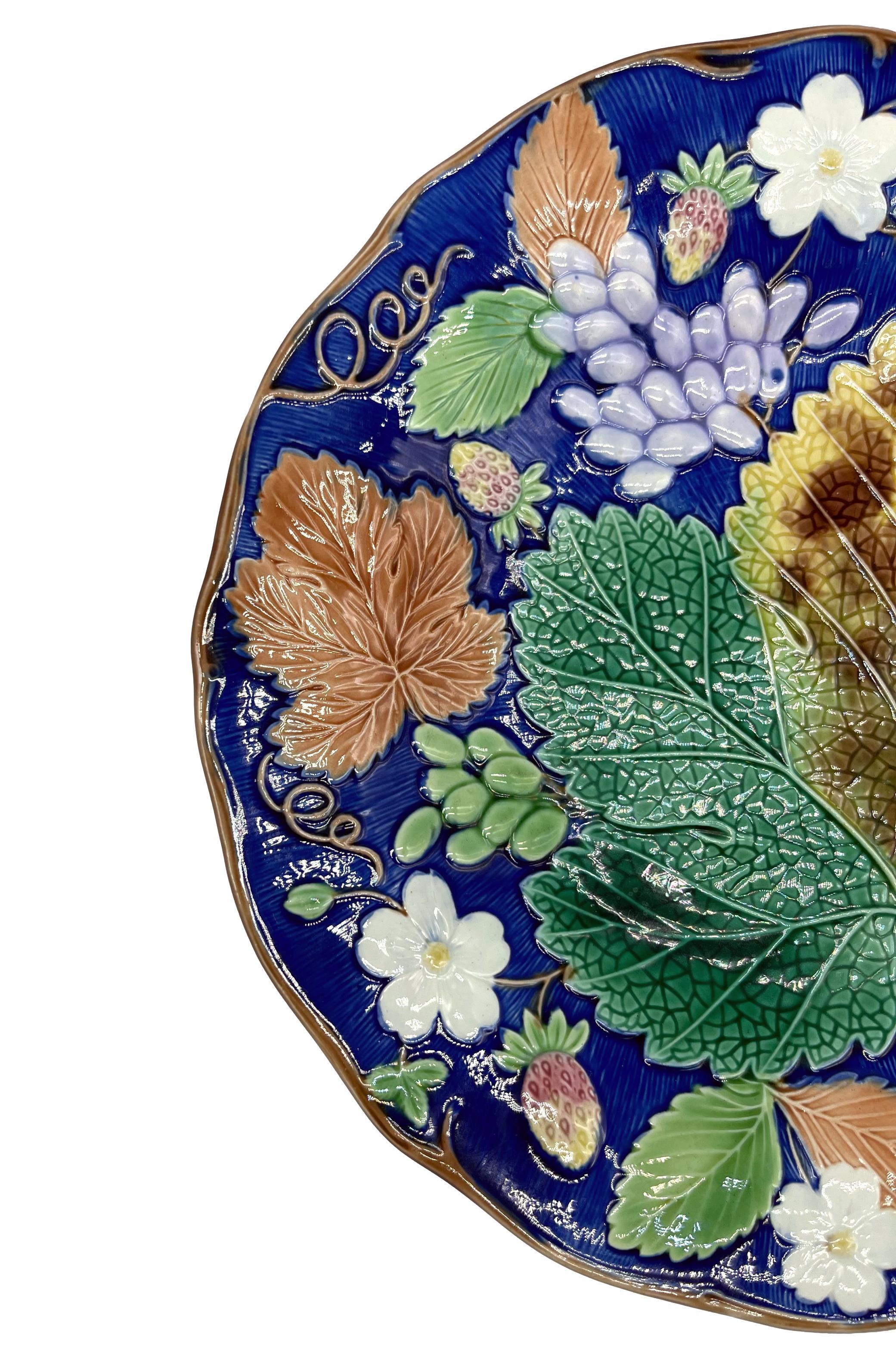 Wedgwood Majolica 'Vine & Strawberry' plate, English, with a large central green grape leaf, purple grapes, strawberries and blossom on a cobalt ground (rare coloration). Impressed marks to reverse: 'WEDGWOOD' and Wedgwood date code for 1878.
For