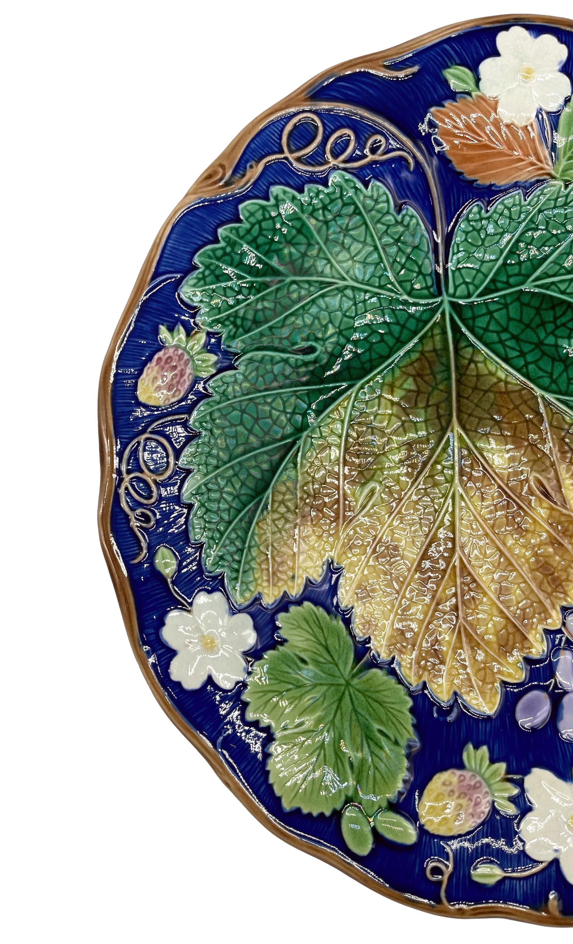 Wedgwood Majolica 'Vine & Strawberry' plate, English, with a large central green grape leaf, purple grapes, strawberries and blossom on a cobalt ground (rare coloration). Impressed marks to reverse: 'WEDGWOOD' and Wedgwood date code for 1878.
For