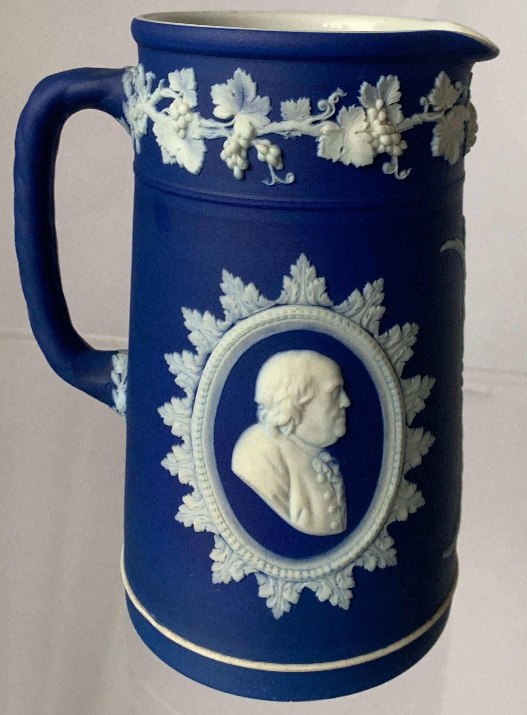 Wedgwood dark blue jasperware tall pitcher featuring neoclassical motif with Founding Fathers Thomas Jefferson and Benjamin Franklin cameos. Inside of the pitcher is glazed. Stamped Wedgwood England on the underside.