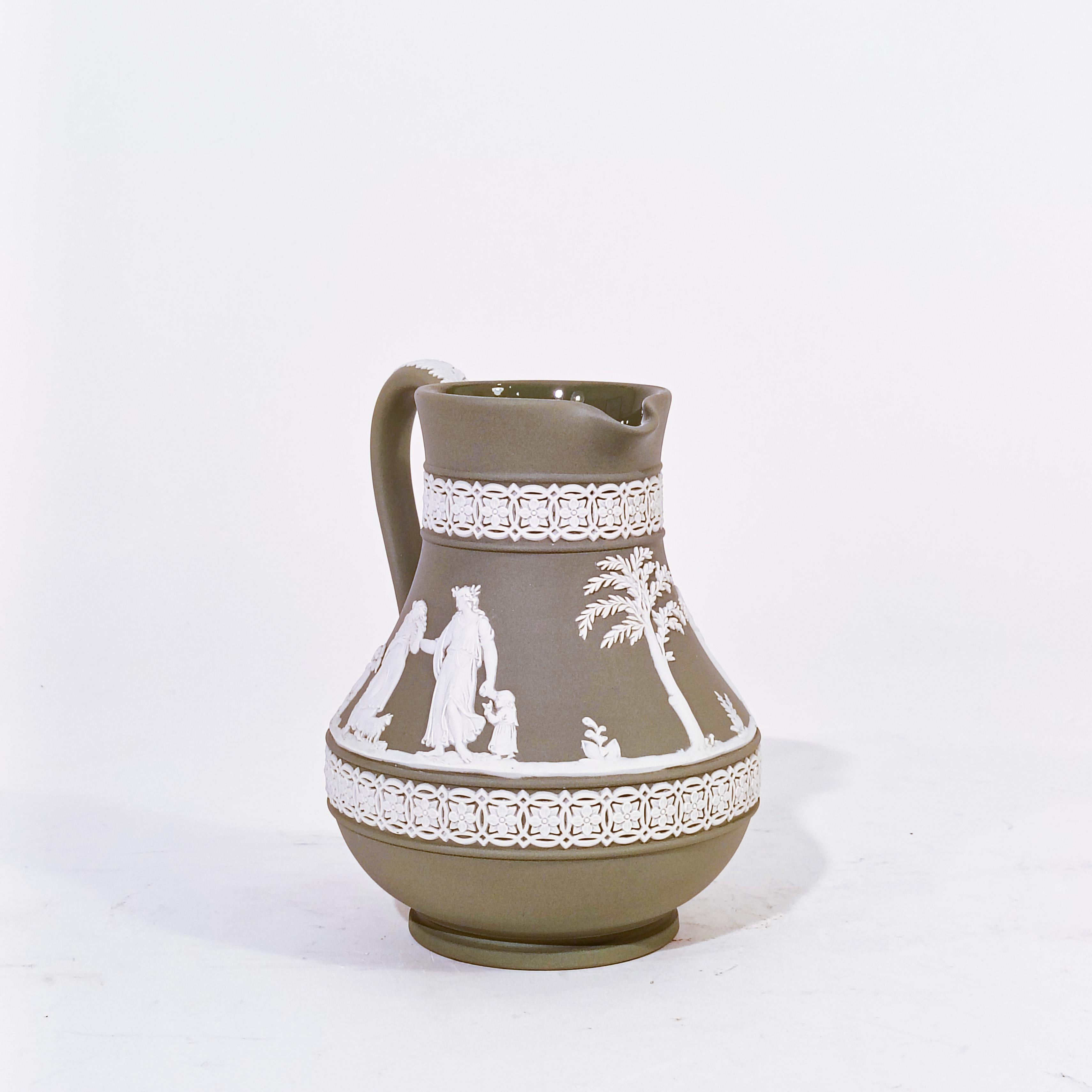 Wedgwood ceramic jug, England, 60s. English ceramic piece in olive green tone and white embossed details representing mythological scenes. Perfect condition. Marked and stamped on the base.

