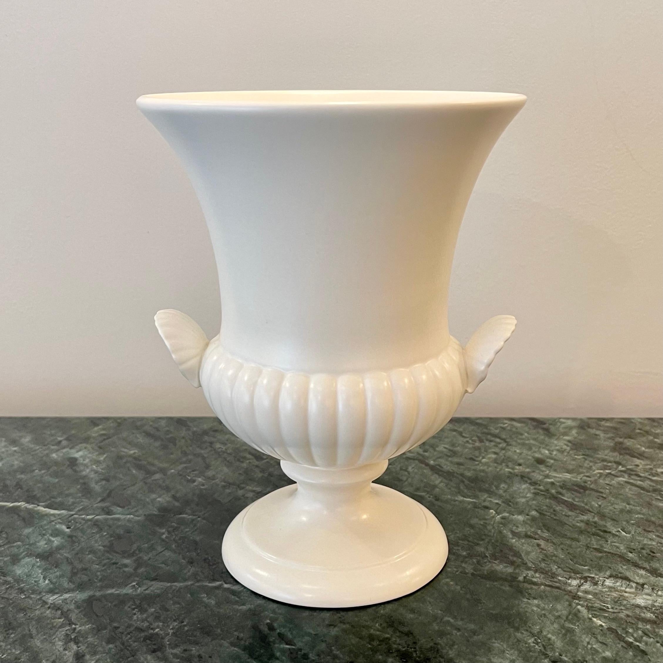 Wedgwood Moonstone Urn Vase, 1960's Norman Wilson Cream Moonstone Glaze, Twin Shell Handled Medici Urn Vase

A beautifully crafted, Wedgwood Queen's Ware, footed urn vase with a ridged lower part and twin shell handles that curve upwards. The