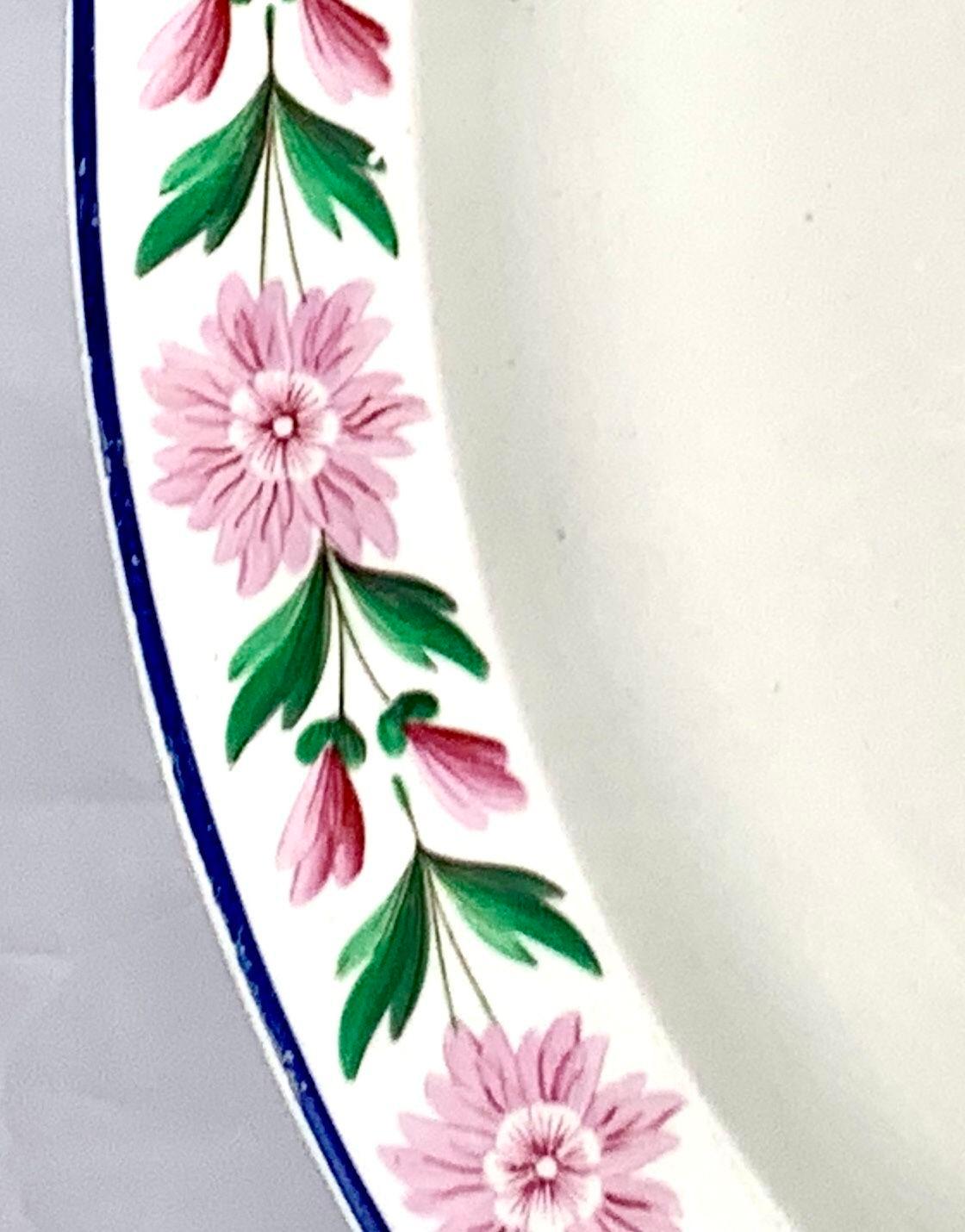 Il s'agit d'un grand plat en creamware de Wedgwood avec une belle bande de marguerites roses avec des feuilles vertes.
Le rose et le vert se complètent parfaitement.
C'est un motif heureux !
Le plateau a été fabriqué en Angleterre vers 1820 et porte