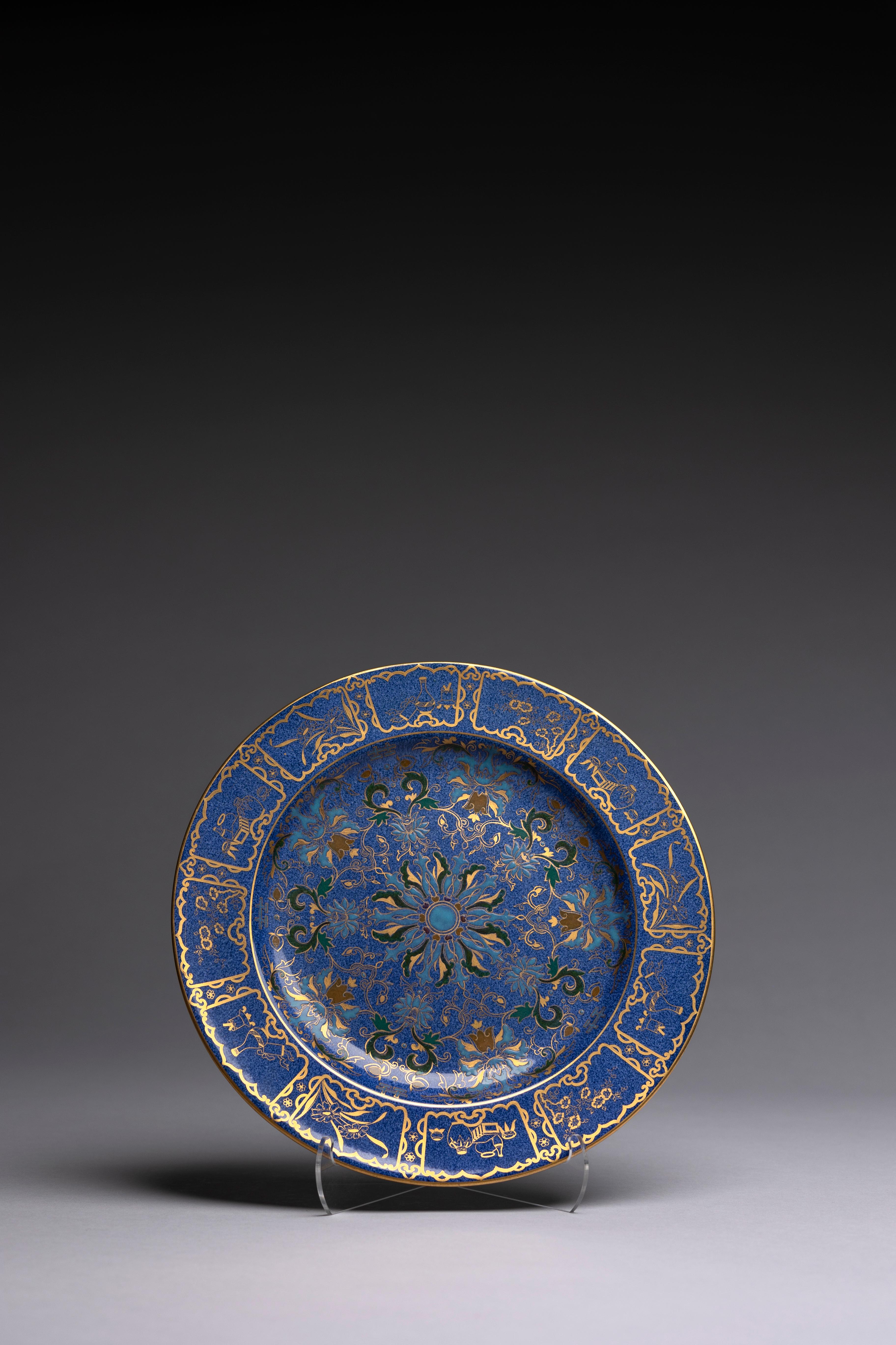 Ein puderblauer Schrankteller, handbemalt von Mabel Tatton für Wedgwood in den 1910er Jahren mit einem aufwendigen vergoldeten Muster.

Dieser von Mabel Tatton um 1912 für Wedgwood handbemalte Kabinettteller zeigt ein zentrales Design in Form eines