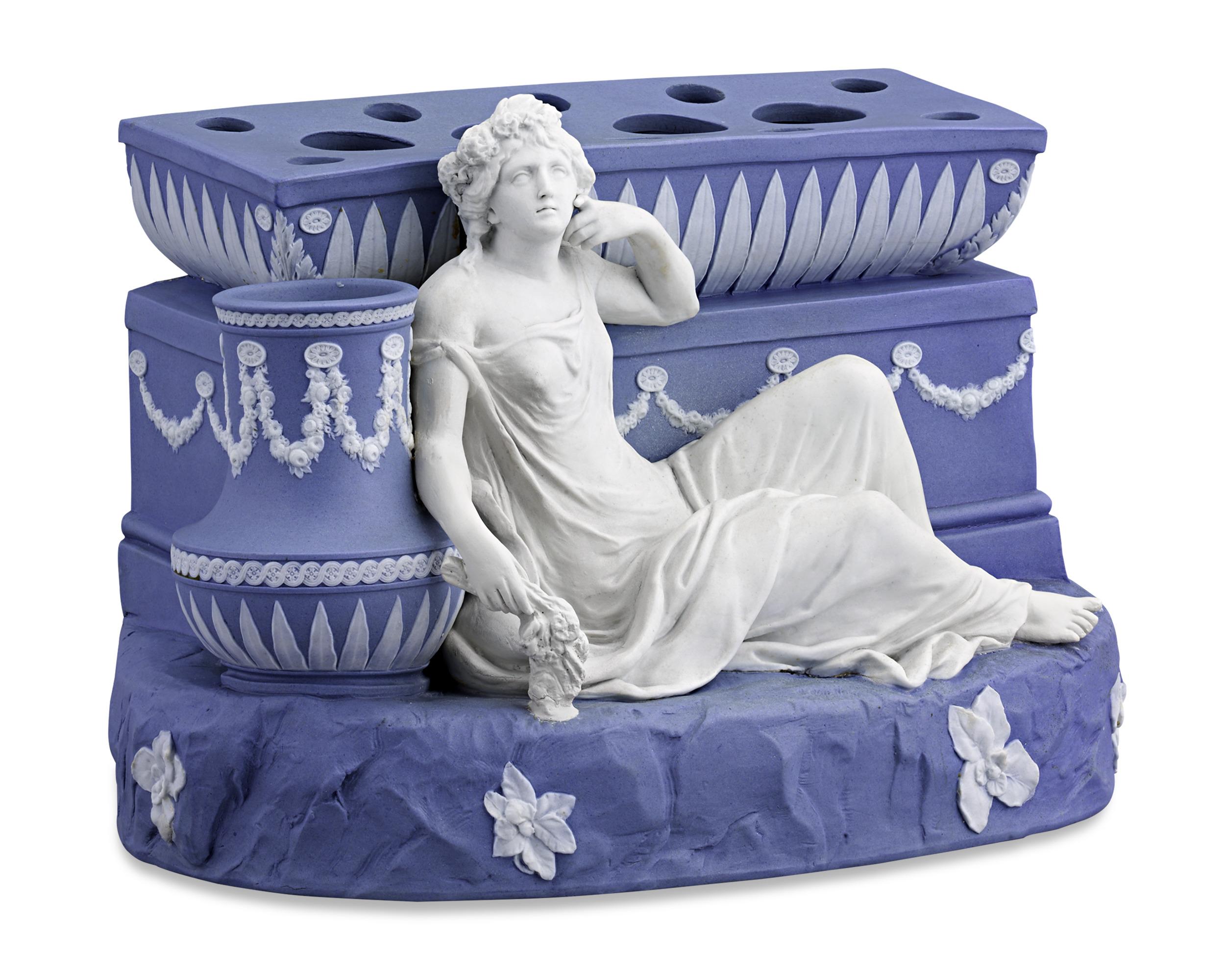 This impressive Wedgwood flower holder is made of the firm’s highly prized blue jasperware with applied white jasper accents. The centerpiece, designed to display “boughs” or flowers, is presented in a stunning Neoclassical motif. The mythological
