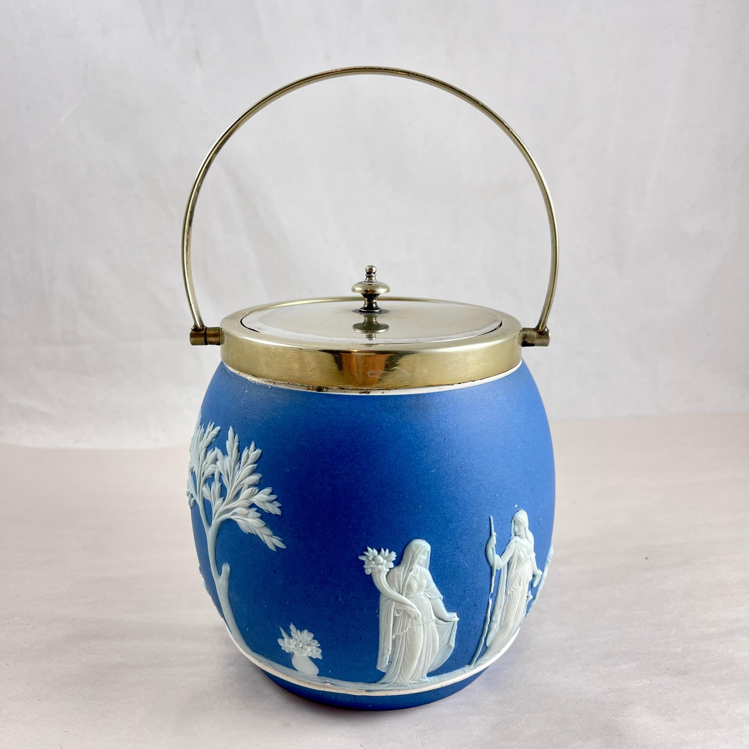 
Ein Wedgwood Jasperware Royal blau Keks Fass mit einem EPNS  Deckel und Bügelgriff, England, um 1910-1930.  

Der tonnenförmige Korpus zeigt ein romantisches, weißes, klassizistisches Muster mit Figuren, Putten und einem großen Baum. 

Eingeprägte