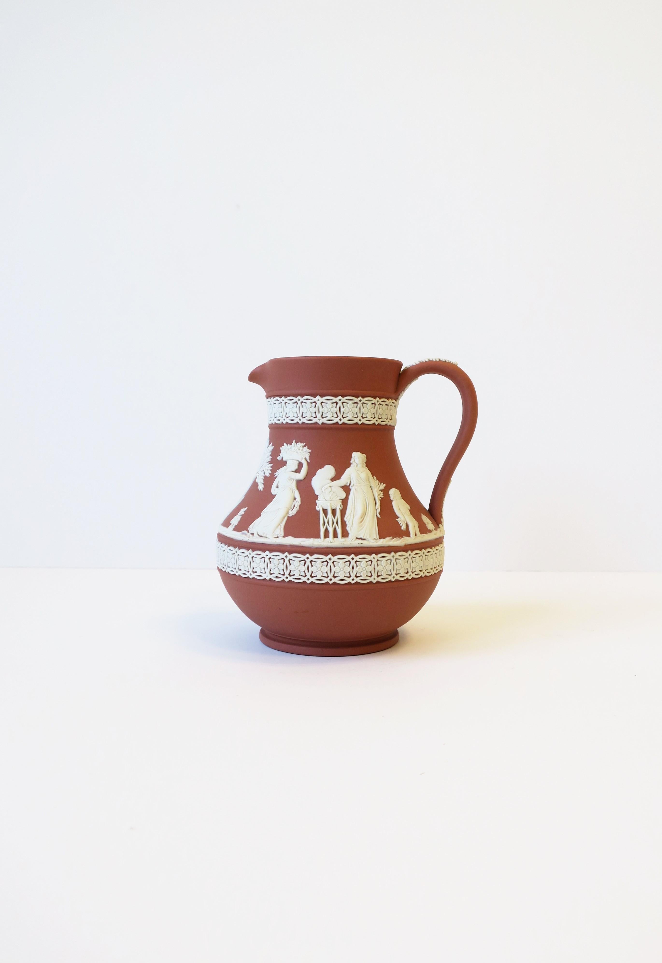 A beautiful and substantial mid-20th century English Wedgwood Jasperware terracotta and white stoneware pitcher in the Neoclassical design style, 1959, England. Piece has a beautiful raised white Neoclassical relief around pitcher's center, a white
