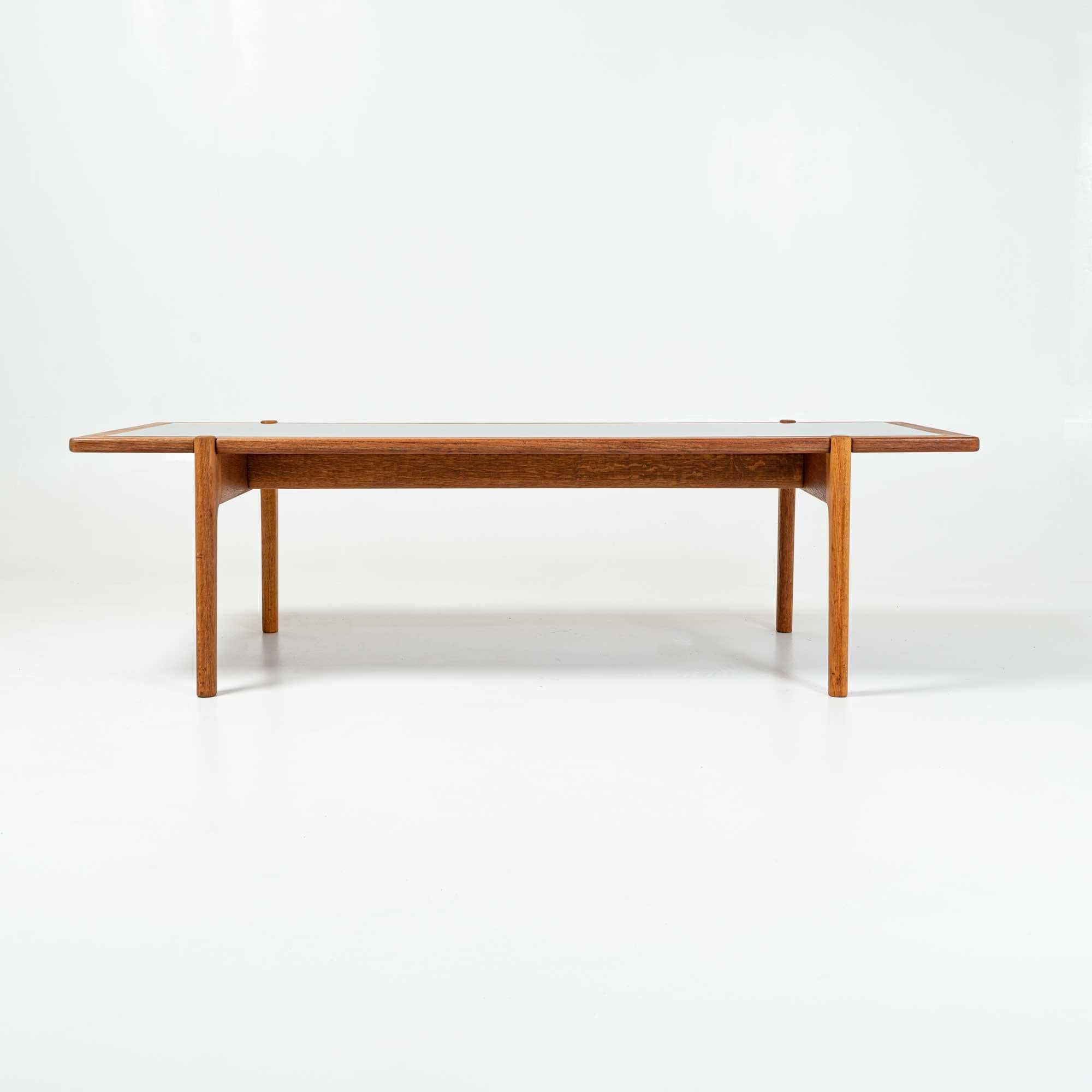 A lesser known design from Hans Wegner, this versatile coffee table with flip top surface featuring black laminate on one side, fully grained teak on the other. The top is resting on a solid oak frame, held together with custom brass bolts and