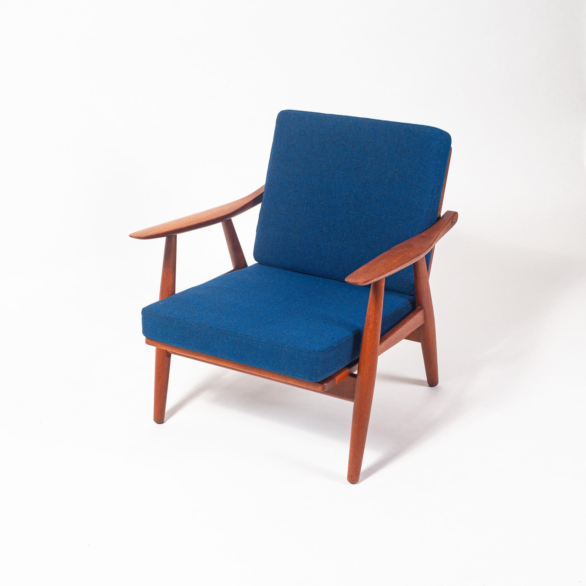 Pair of Hans Wegner GE-270 lounge chairs in solid teak and new royal blue wool upholstery, circa 1950s. This lounge chair has a sculpted solid teak frame with exposed, bespoke brass fittings. Unlike the Wegner Cigar Series or other lounge chairs,