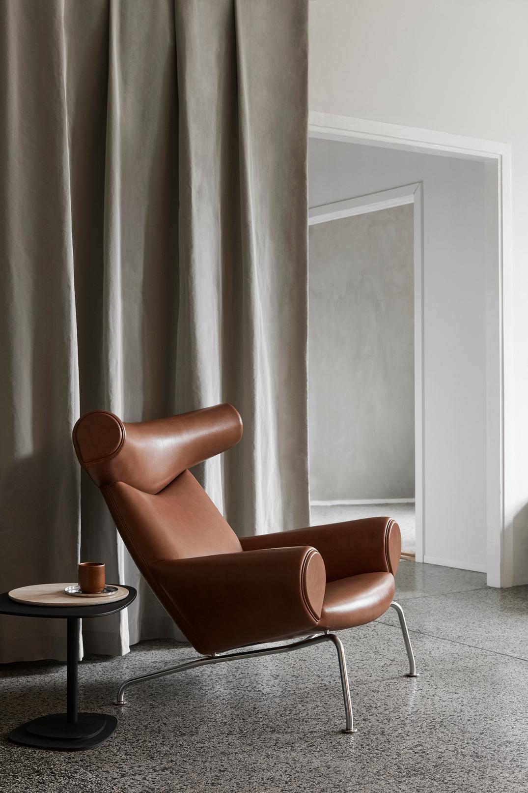 Der von Hans J. Wegner entworfene Ox Chair ist ein ikonisches Möbelstück mit unbestreitbarer Präsenz. Ein kühner, skulpturaler Stuhl, der mit seiner markanten, an Ochsenhörner erinnernden Kopfstütze und seinem voluminösen Körper die zurückhaltende