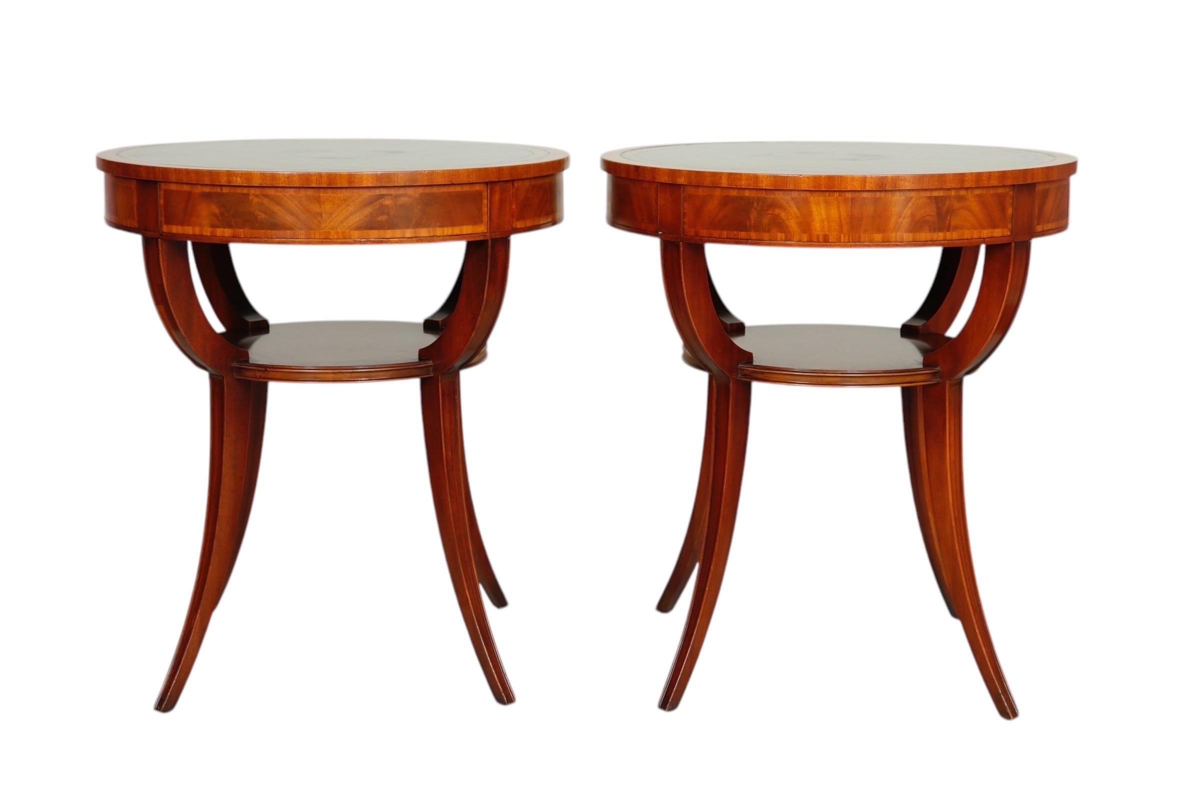 Zwei zweistöckige Salontische im Biedermeier-Stil, hergestellt von Weiman Möbel, um 1950. Die runden Tischplatten sind mit grünem Leder mit goldfarbener Umrandung bezogen, und die Zargen sind mit geflammten Mahagoni-Furnierplatten verziert.