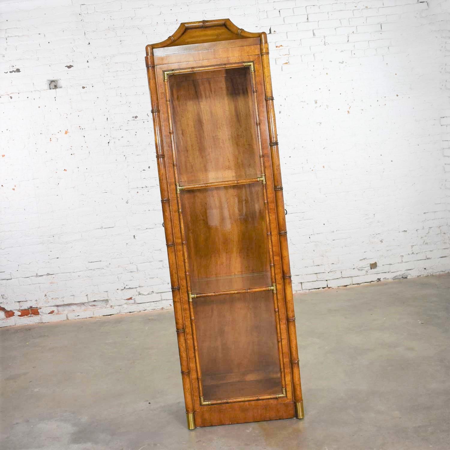 Handsome narrow lighted display cabinet in a Hollywood Regency Campaign faux bamboo style by Weiman. It is in incredible vintage condition with no outstanding flaws. Please see photos, circa 1970s.

This is the second cabinet like this we have had