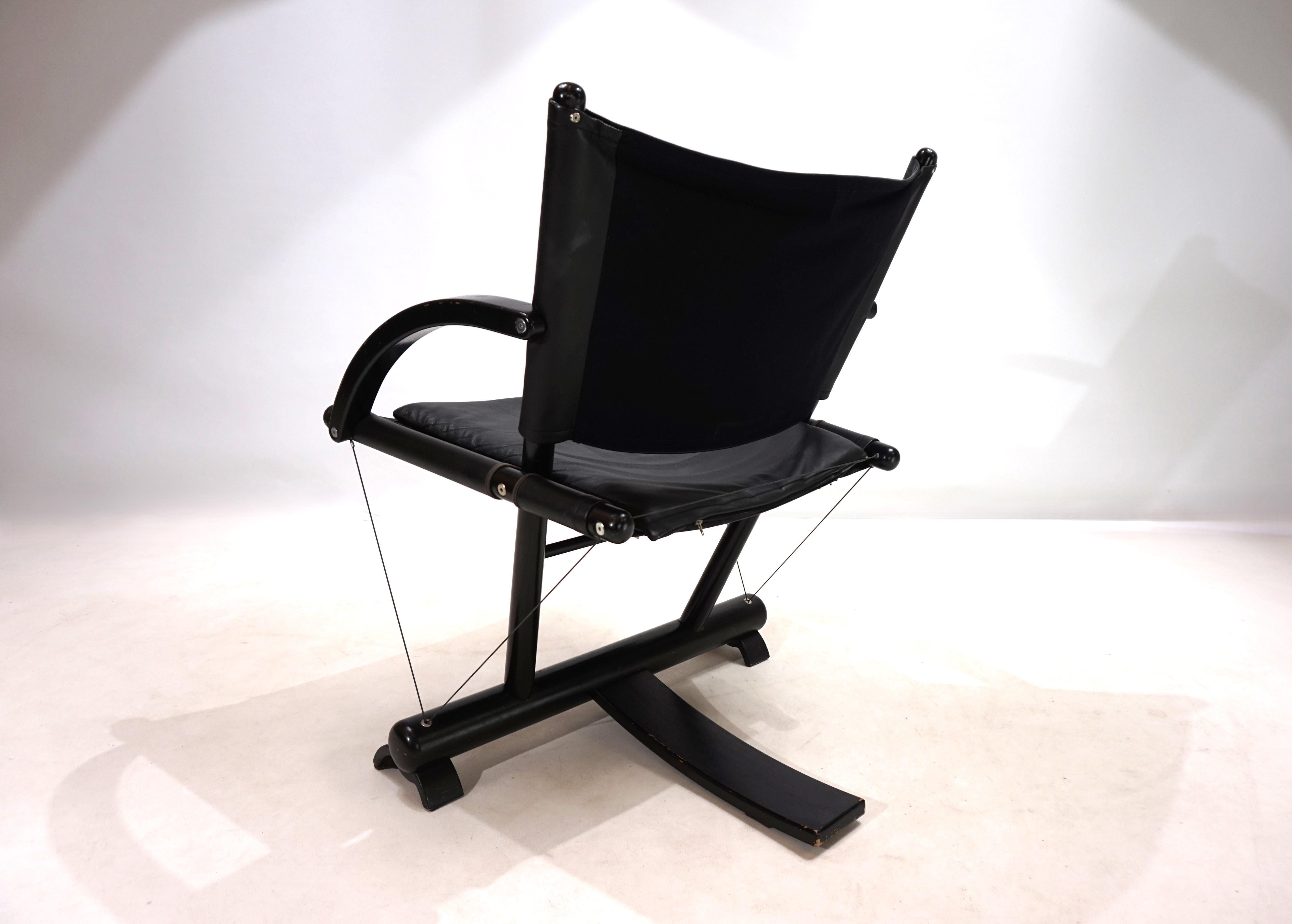 Una tumbona inusual y de diseño inteligente en el estilo posmoderno de los años 80. El armazón de la silla, de madera negra, se fija mediante cables de acero tensados y, al mismo tiempo, se mantiene lo suficientemente flexible como para dar la