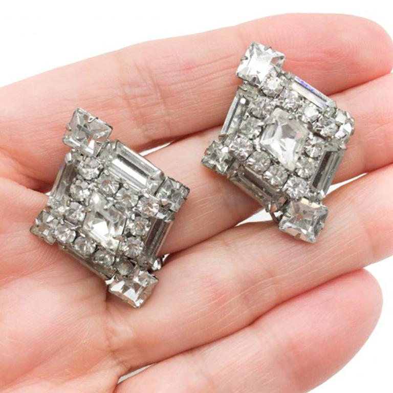 A super pair of Vintage Weiss Rhinestone Earrings hailing from the 1950s. These clip on Weiss Rhinestone Earrings feature a distinctive lozenge shape setting crammed with a clever arrangement of individually claw set fancy cut crystal rhinestones in