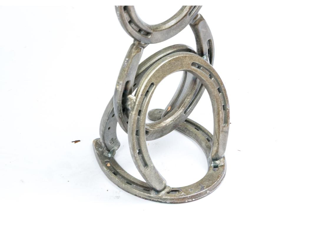 Eine dynamische Vitrine zum Thema Western mit geschliffenen Stahlpferden, geschweißten, gestapelten Hufeisenbeinen und Griffen in Pistolenform. Der verriegelte Deckel (mit einem Schlüssel) lässt sich öffnen und gibt den Blick auf eine große