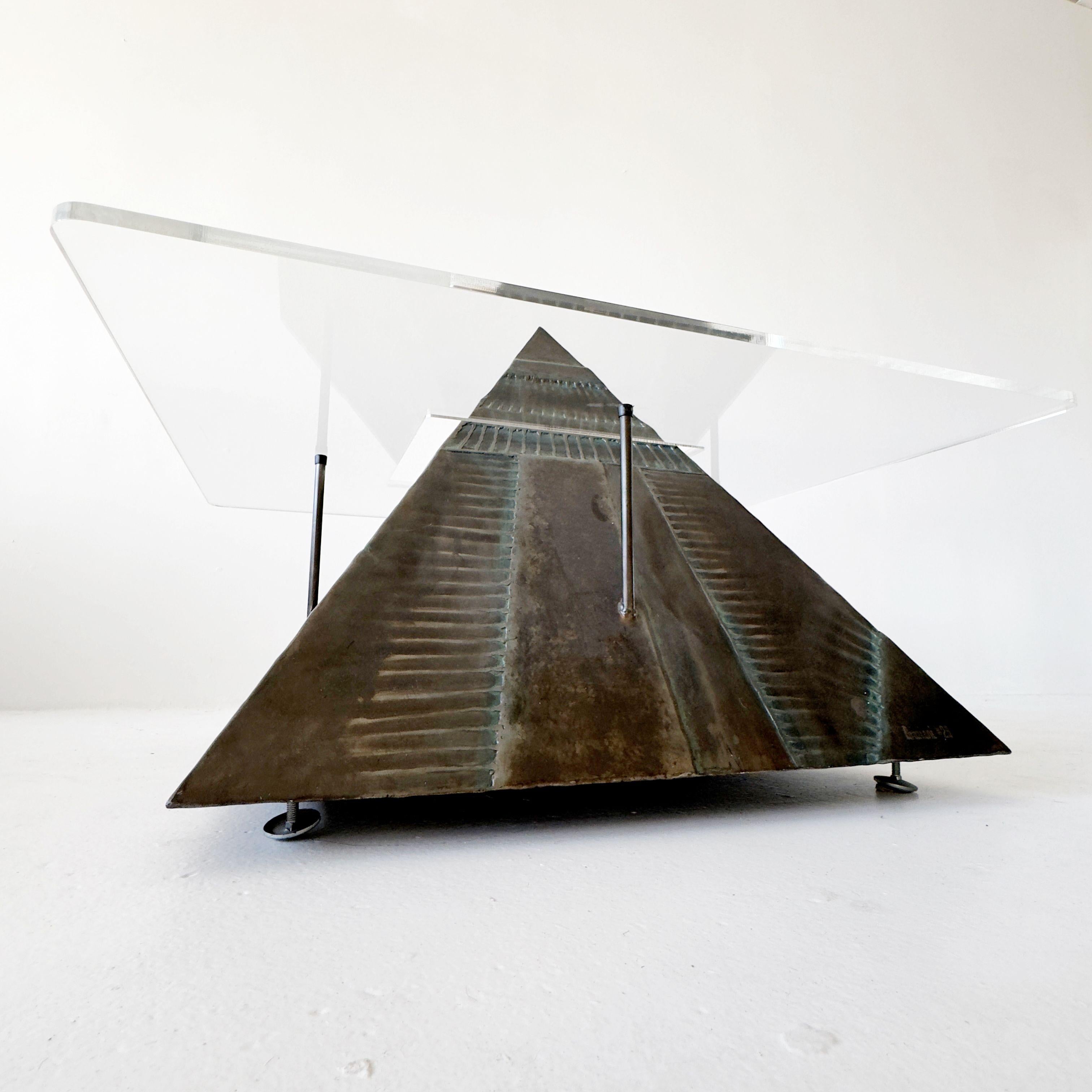 welded metal levitating pyramid coffee table made by a local LA artist in the 1990s. The surface of the sculpture is textured and a burnished bronze finish with some turquoise undertones. The table top is a heavy transparent acrylic that wraps