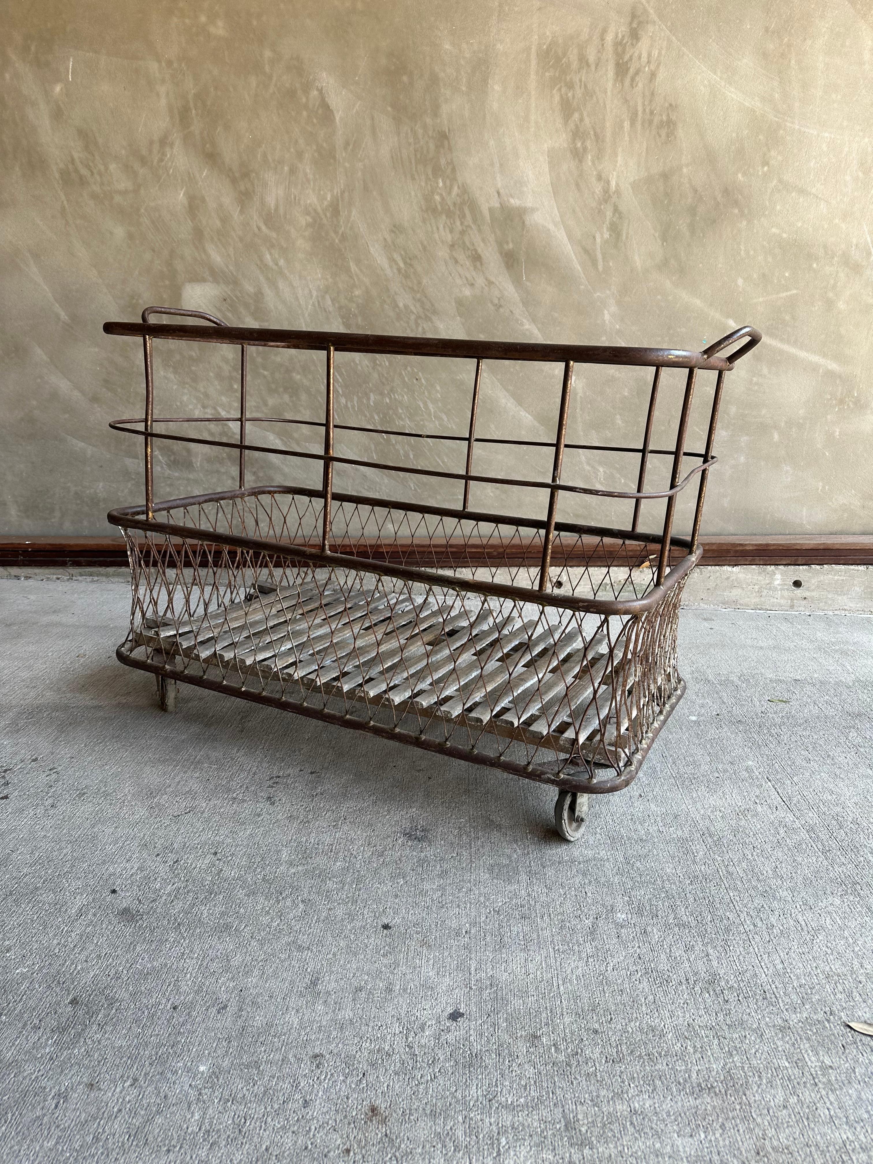A French metal cart, basket, trolley with slatted wood at base, wheels, and basket weave sides. Understood to originally have been a cart for delivering French bread to market. France, late 19th century.