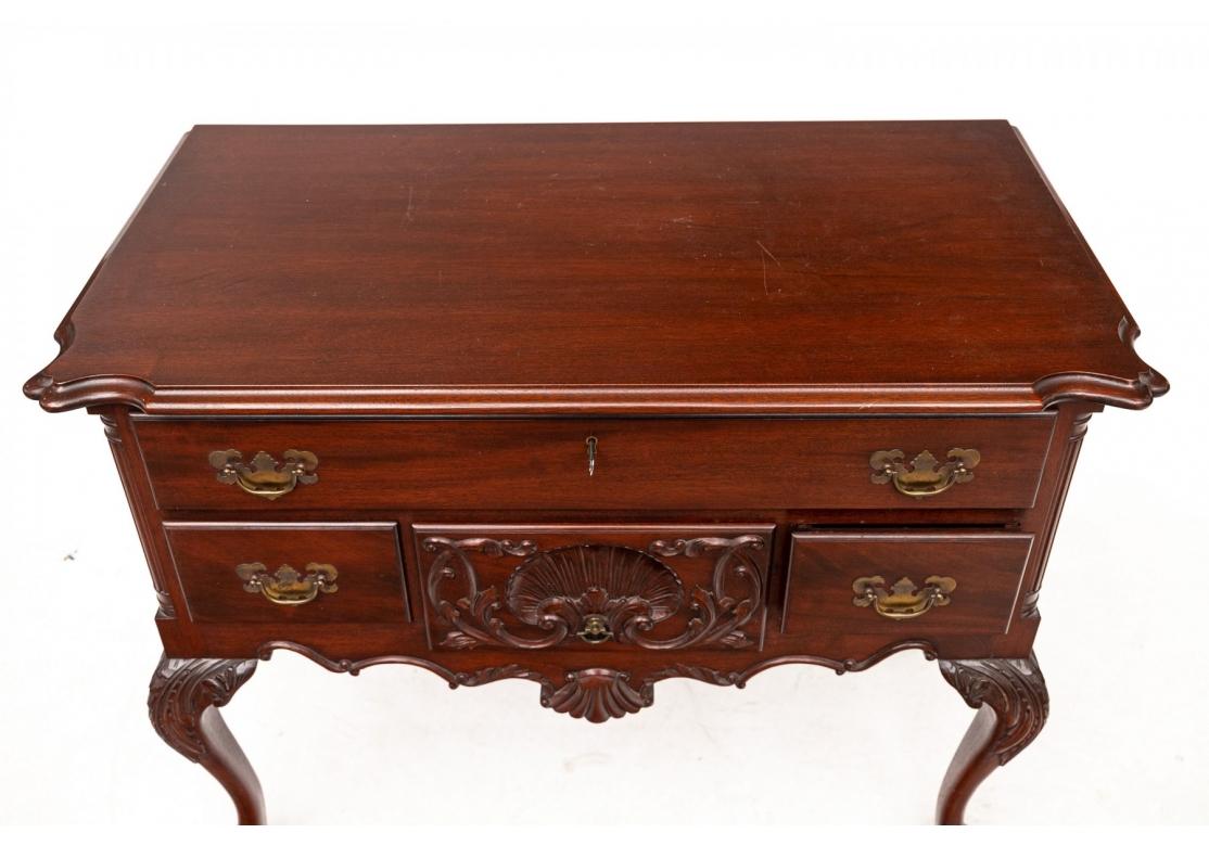 Vintage Chippendale style low boy with a scalloped edge over top drawer with three divided drawers accented with brass hardware, the middle drawer with a deeply carved Shell motif. Standing upon cabriole legs ending in claw and ball feet.