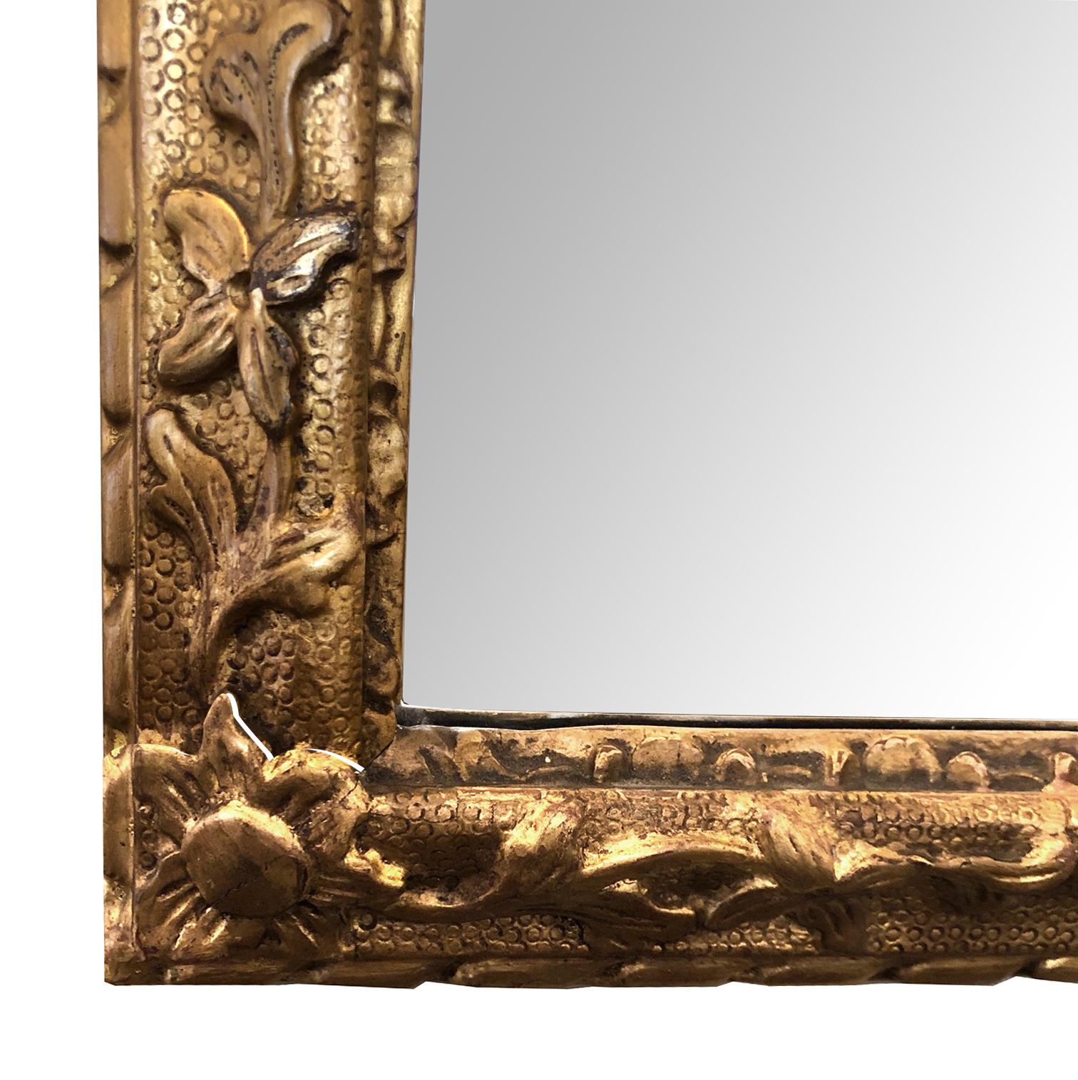 The exuberantly carved openwork crest composed of dramatic interlacing C-scroll motifs with floral and foliate elements cascading down the sides; all surrounding the original beveled mirror plate within a relief-carved molding.