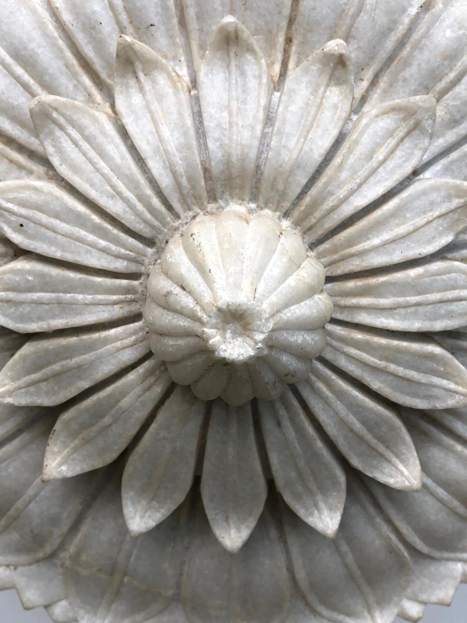 Un élément floral bien sculpté en marbre translucide, posé sur une base en acier faite sur mesure.