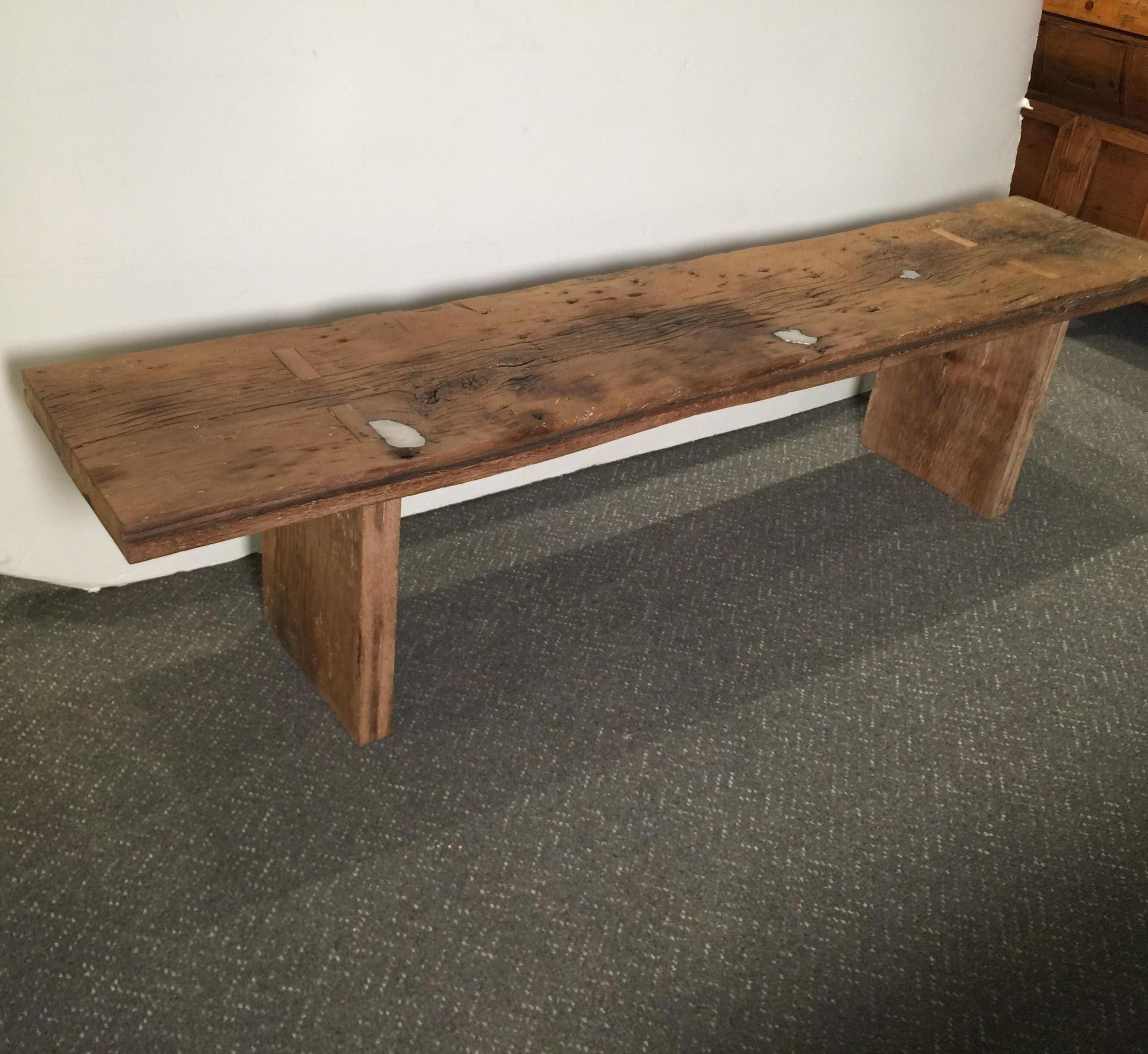 Unusual bench of coffee table made from a thick piece of barn wood well over a century old showing beautiful character and age. The aged wood has had the knots poured with pewter which give this both a Primitive as well as an Industrial feel. One of