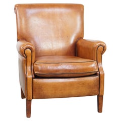 Well-maintained sheepskin leather armchair neatly finished with black piping