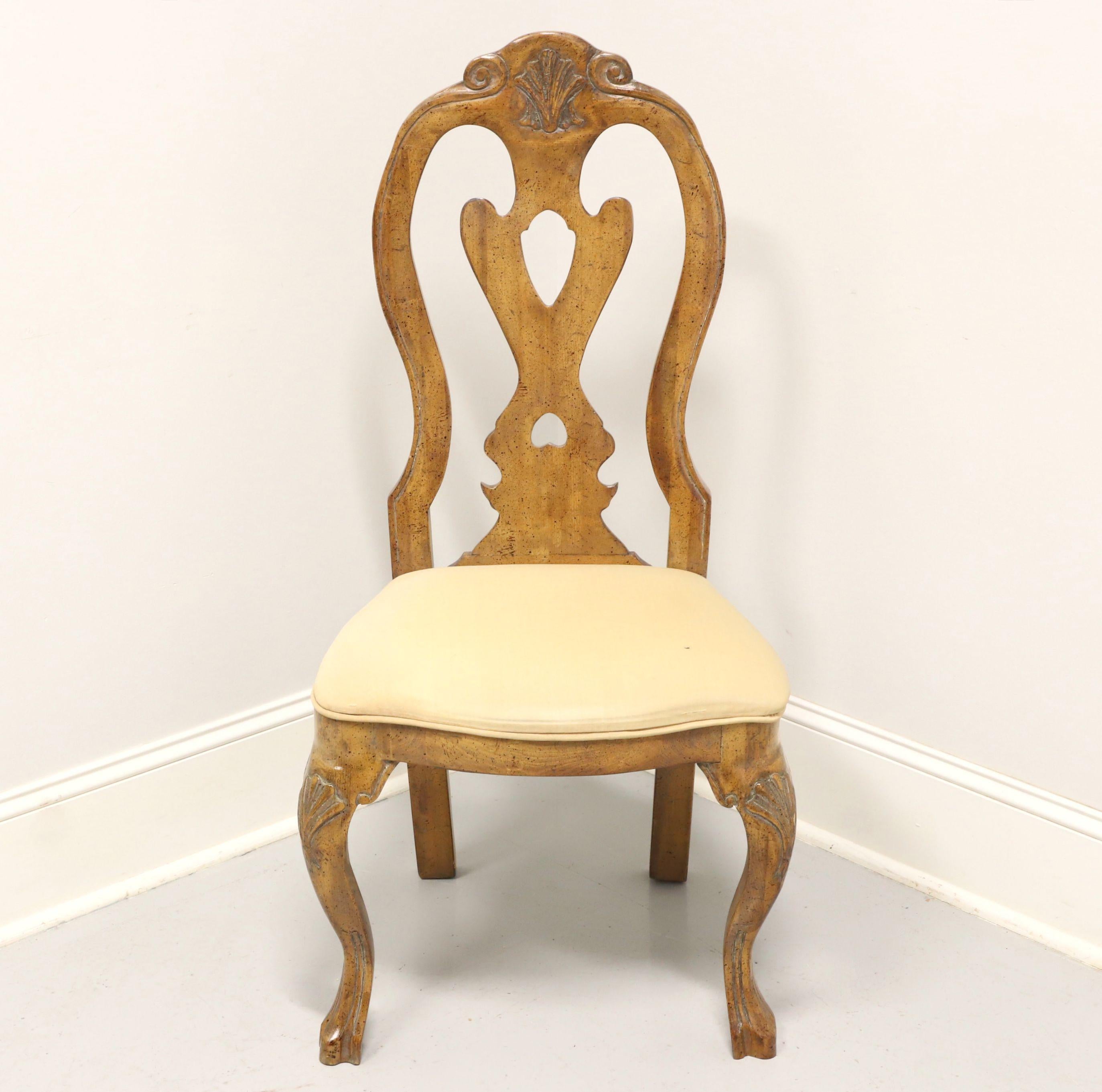 A French Country style side chair by Wellesley Guild. Hand carved & crafted of walnut with a distressed finish, highly carved crest rail, carved center backrest, upholstered seat in a neutral cream color fabric, carved knees, cabriole legs and paw