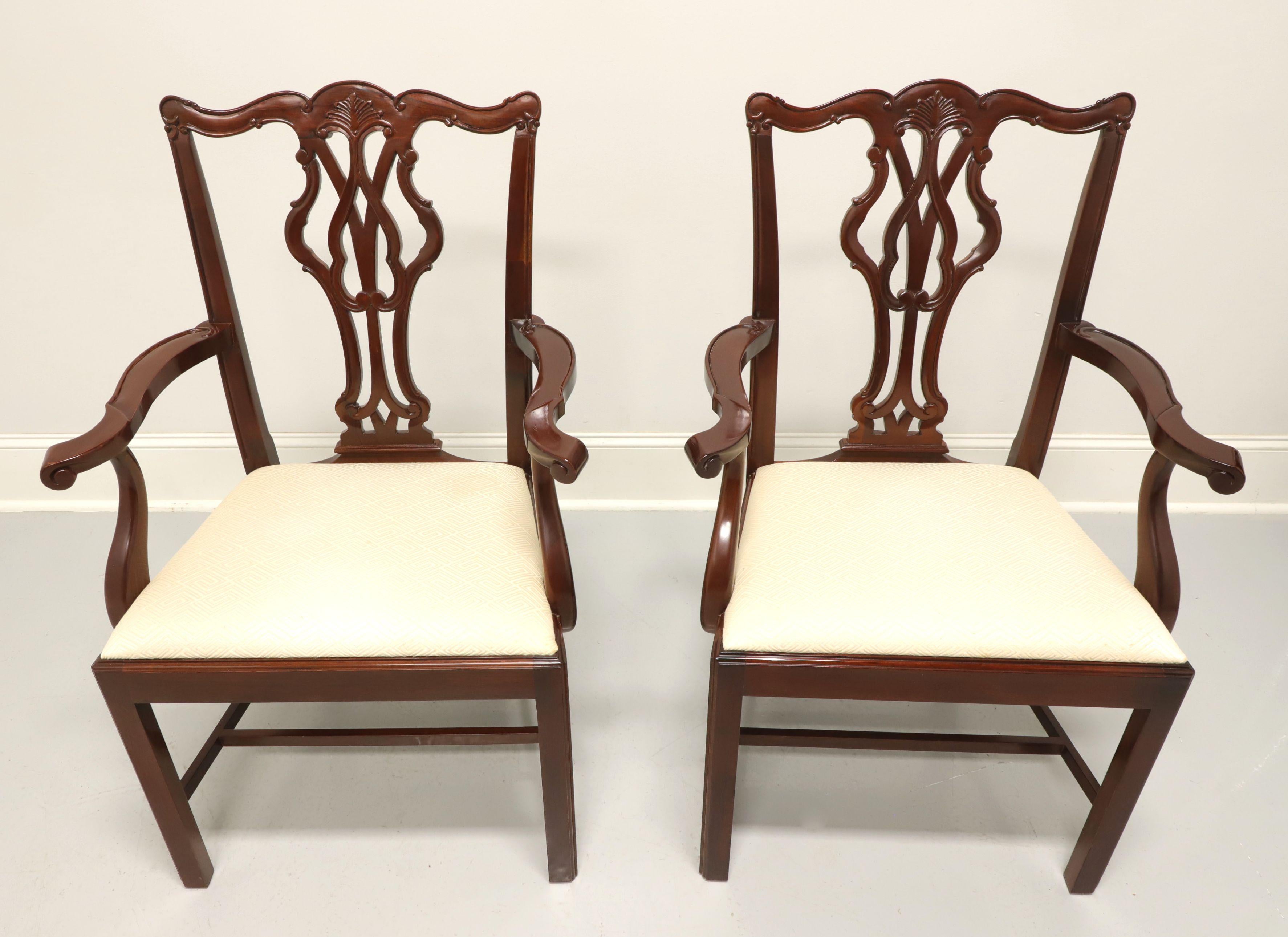 A pair of dining armchairs in the Chippendale style by Wellington Hall. Solid mahogany with carved crestrail, curved arms, carved seat back, cream color geometric pattern upholstered seat, straight legs and stretchers. Made in North Carolina, USA,
